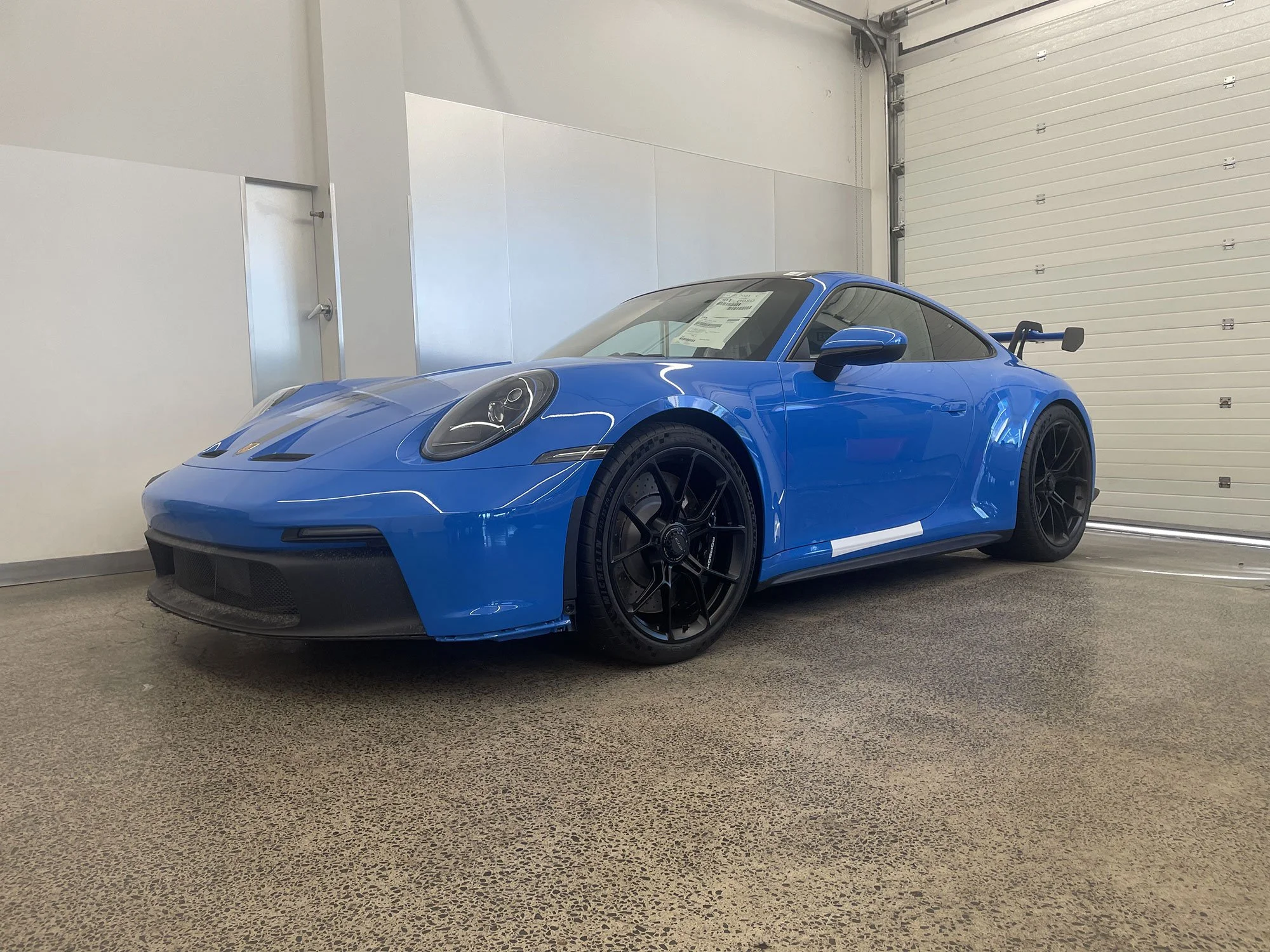 Blue Porsche sports car inside a garage with a white door