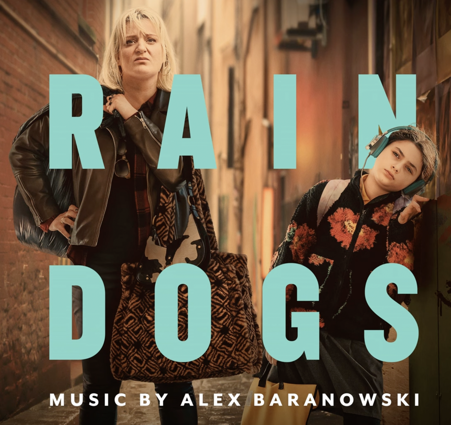 Two women, one older and one younger, walking in an alleyway with graffiti walls. The older woman looks concerned, while the younger woman wears headphones and leans against the wall. Overlaid text reads 'rain Dogs' with smaller text 'Music by Alex Baranowski.'