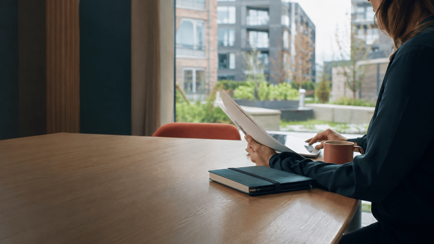 Illustrative housing professional reviewing records beside a window overlooking a residential courtyard.