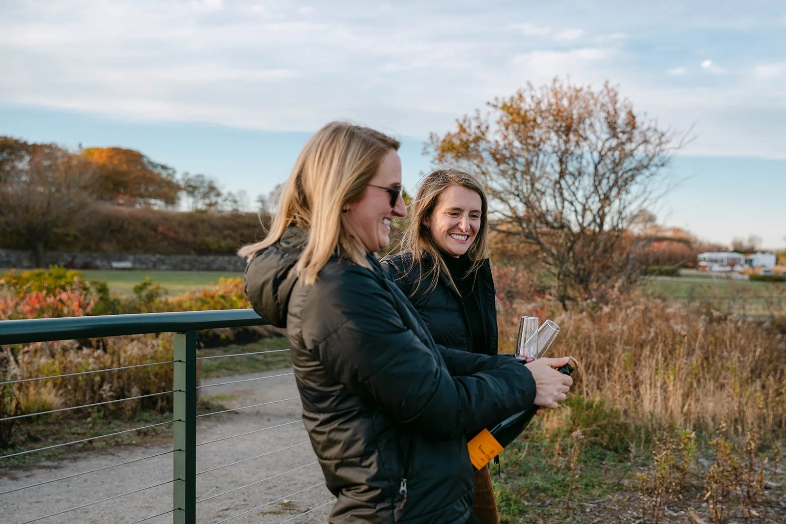 newly engaged couple celebrating with champagne overlooking a lighthouse in maine
