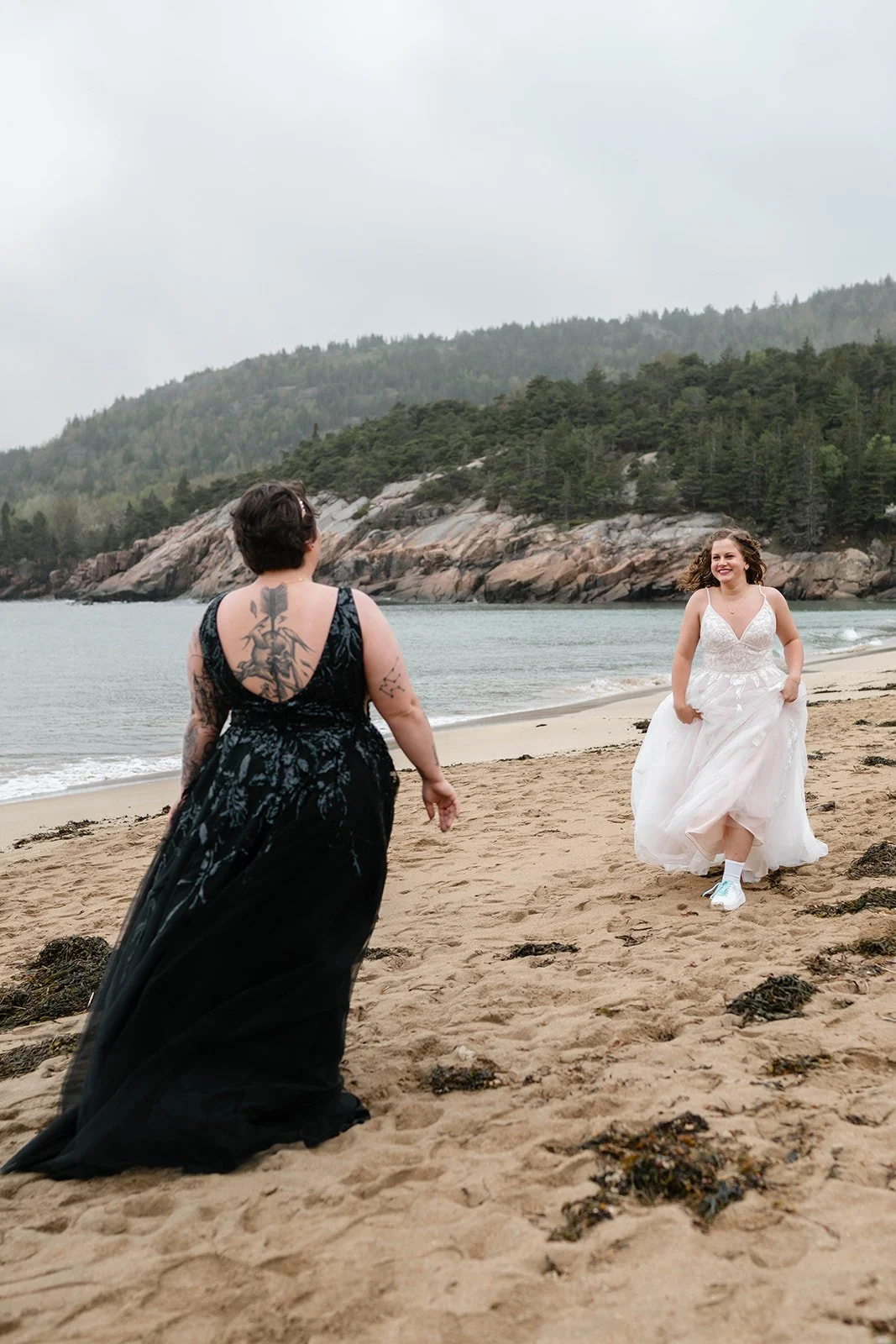 playful brides running around along sand beach shores in acadia