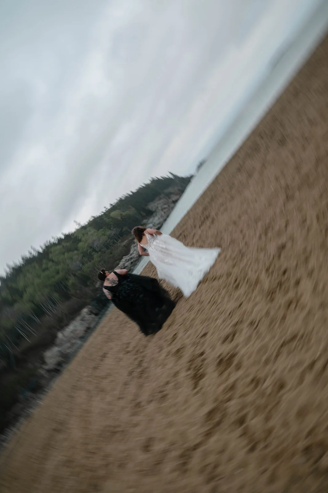 playful brides running around along sand beach shores in acadia