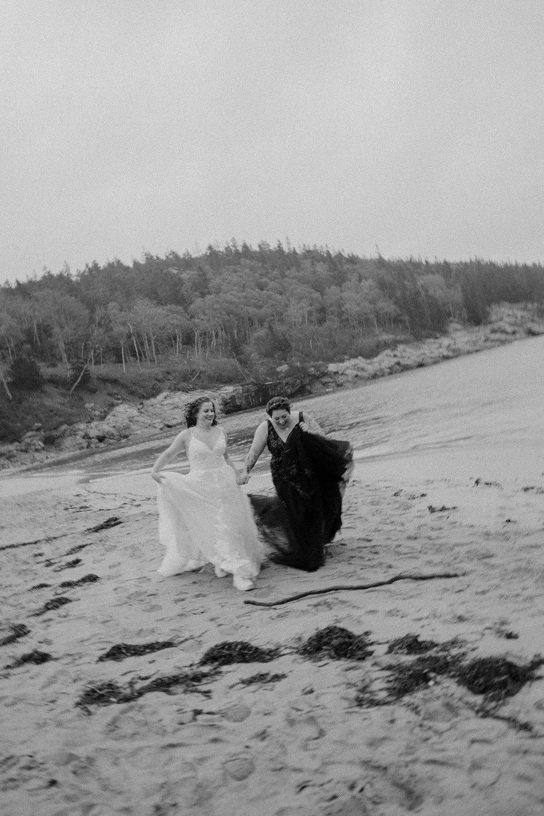 playful brides running around along sand beach shores in acadia