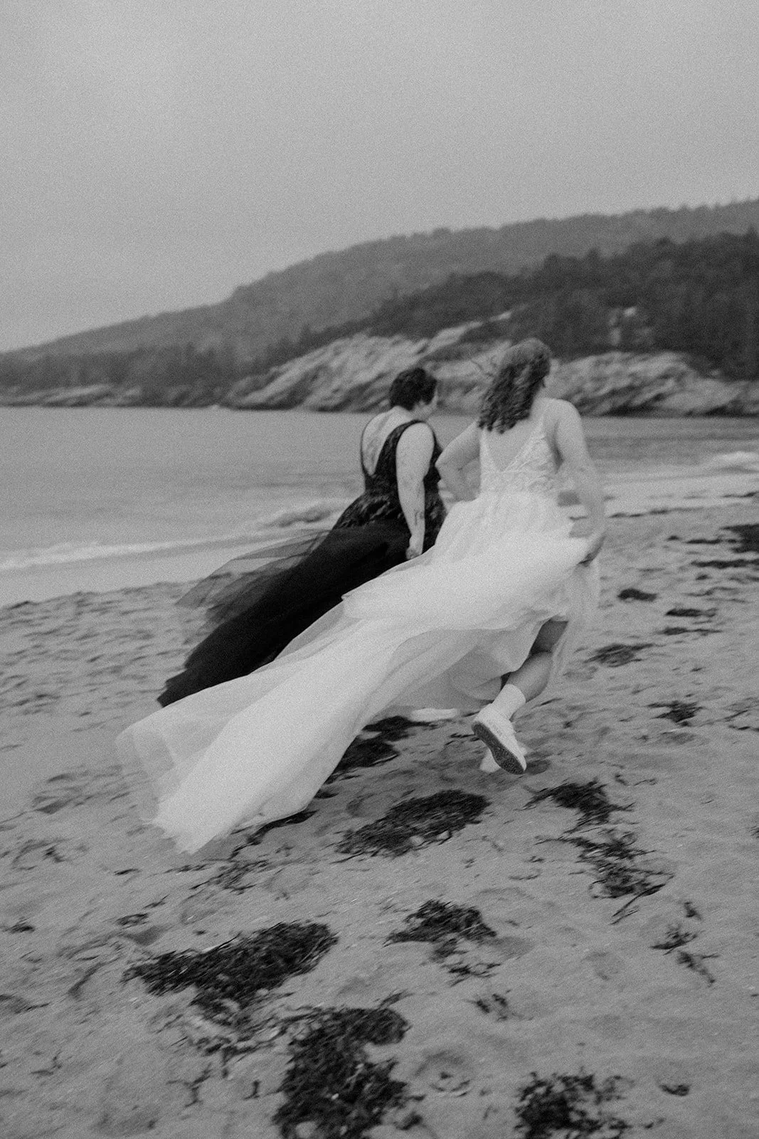 playful brides running around along sand beach shores in acadia