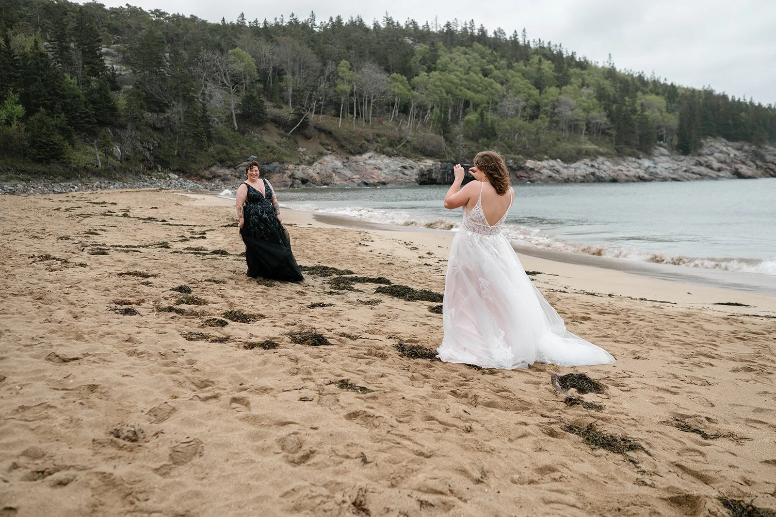 playful brides running around along sand beach shores in acadia