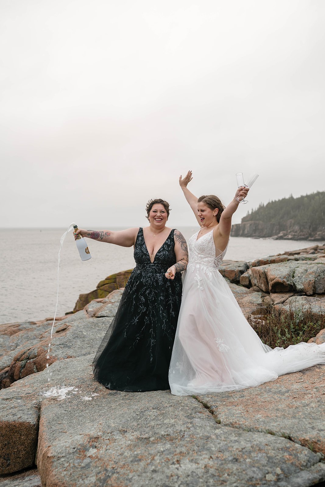 brides celebrating their elopement with a champagne toast at monument cove in acadia national park