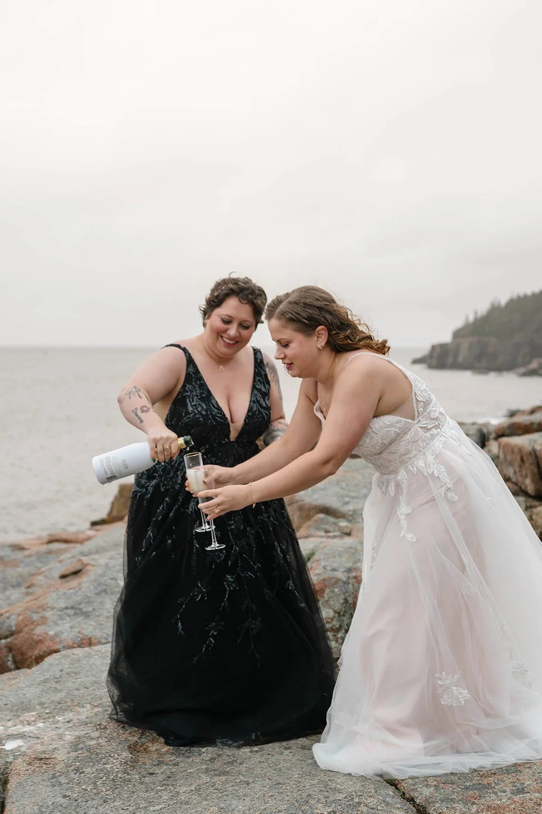brides celebrating their elopement with a champagne toast at monument cove in acadia national park