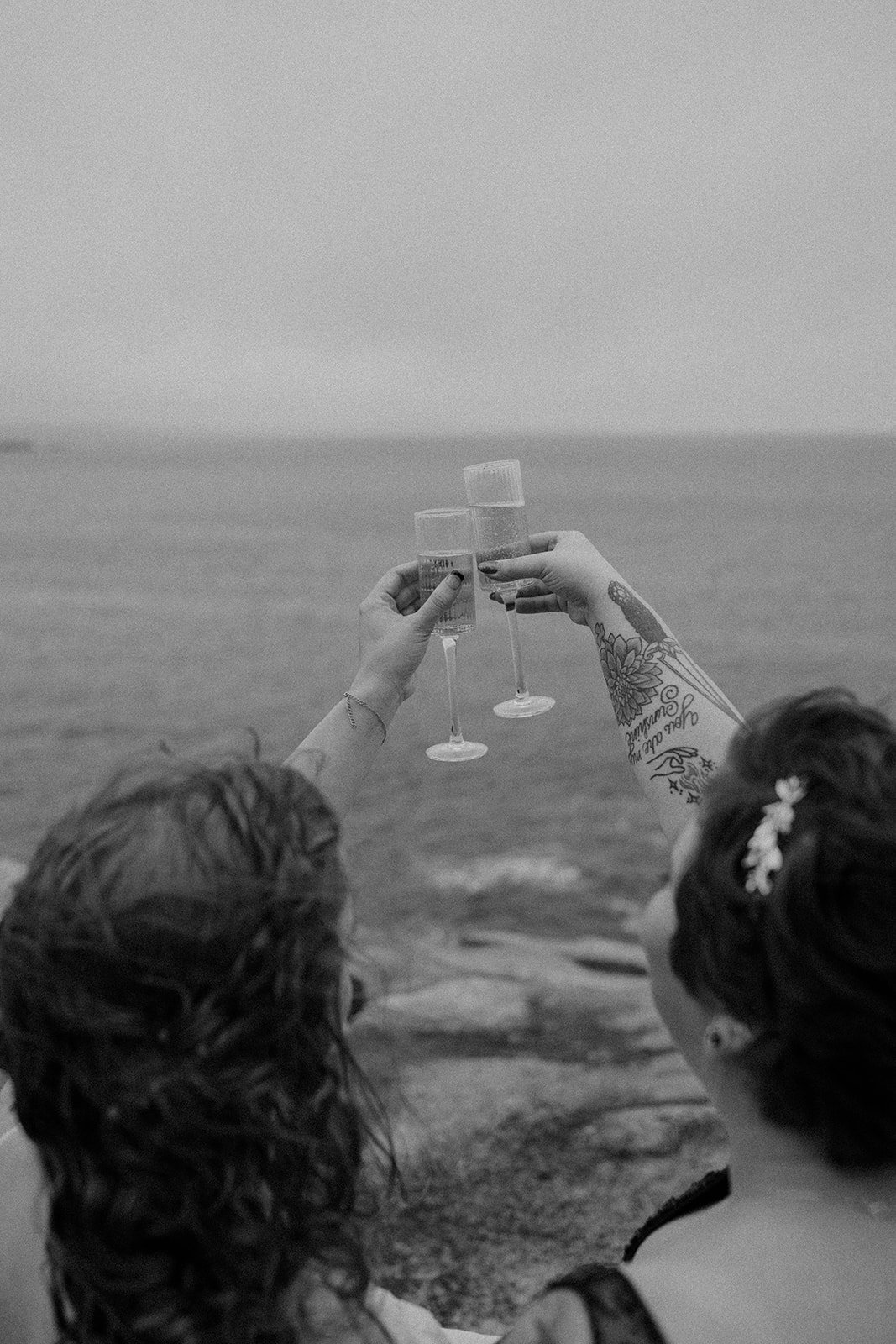brides celebrating their elopement with a champagne toast at monument cove in acadia national park