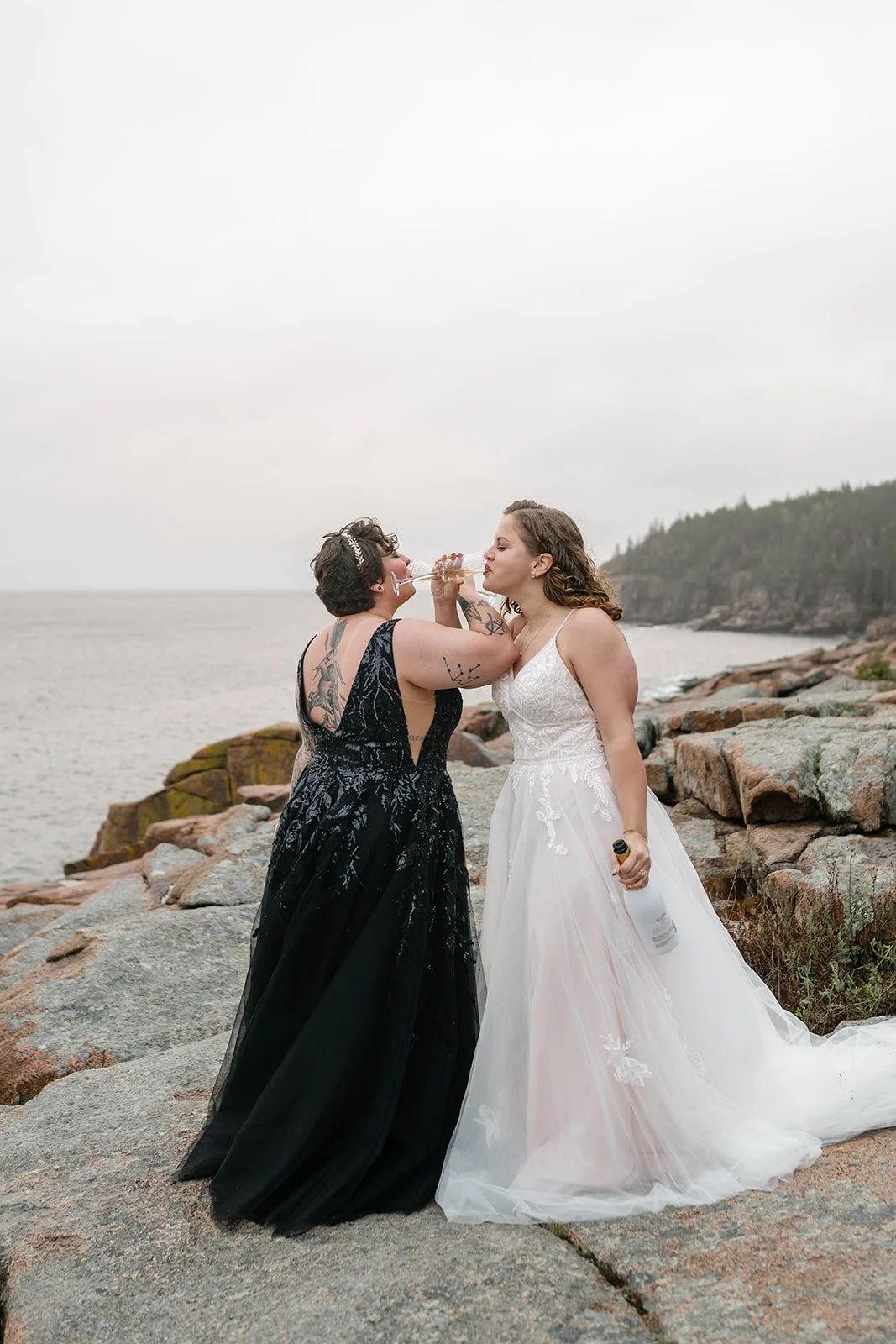 brides celebrating their elopement with a champagne toast at monument cove in acadia national park