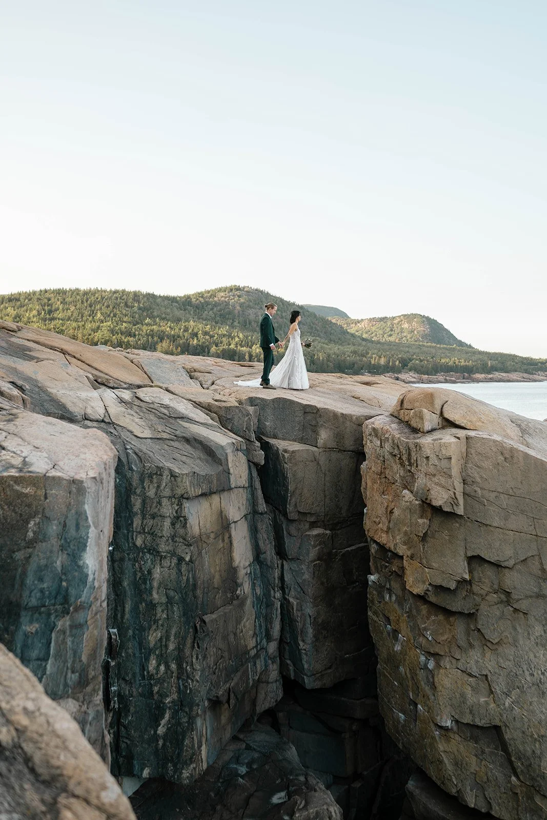 bride and groom hiking at otter cliff overlook in acadia national park
