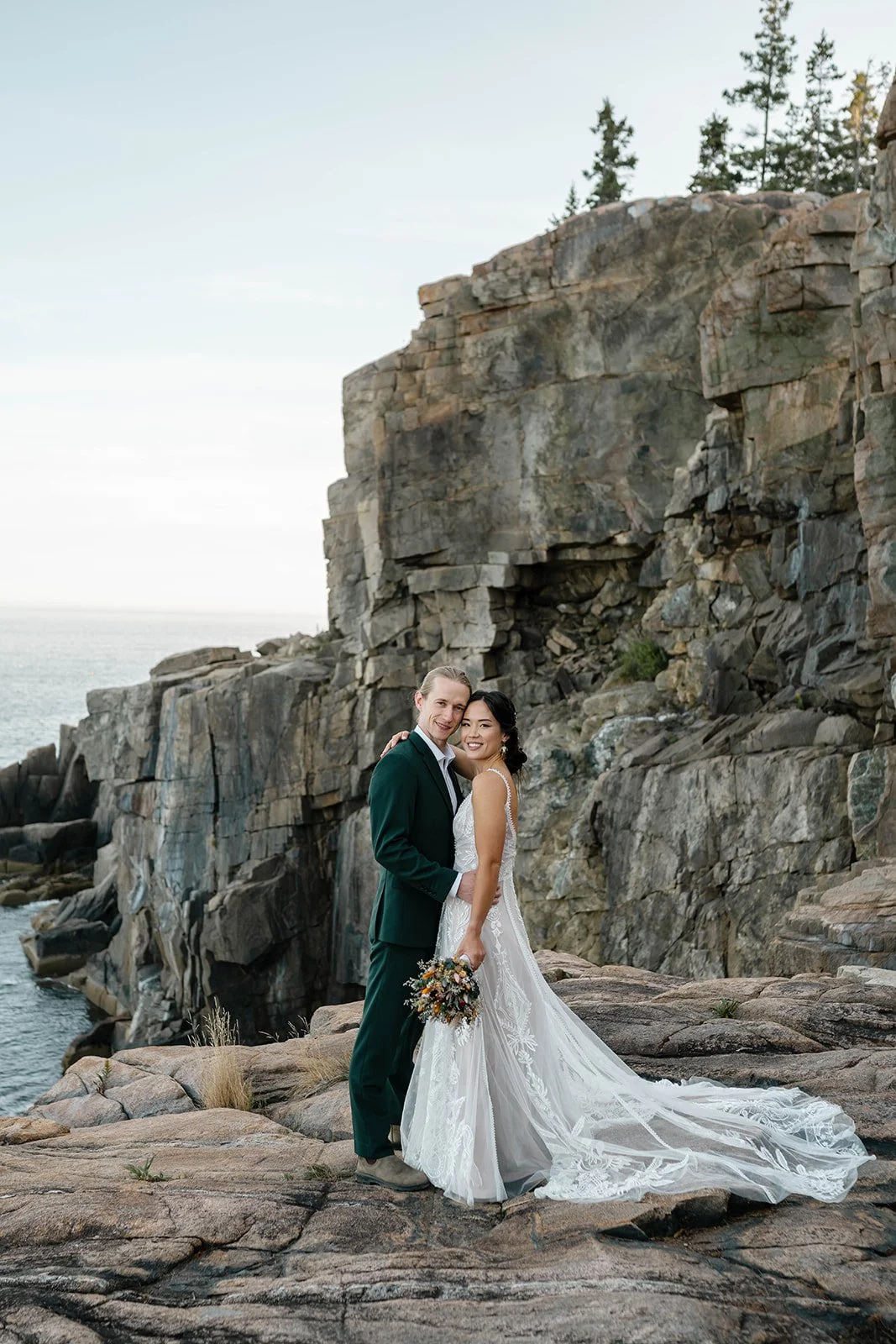 bride and groom standing at otter cliff overlook in acadia national park