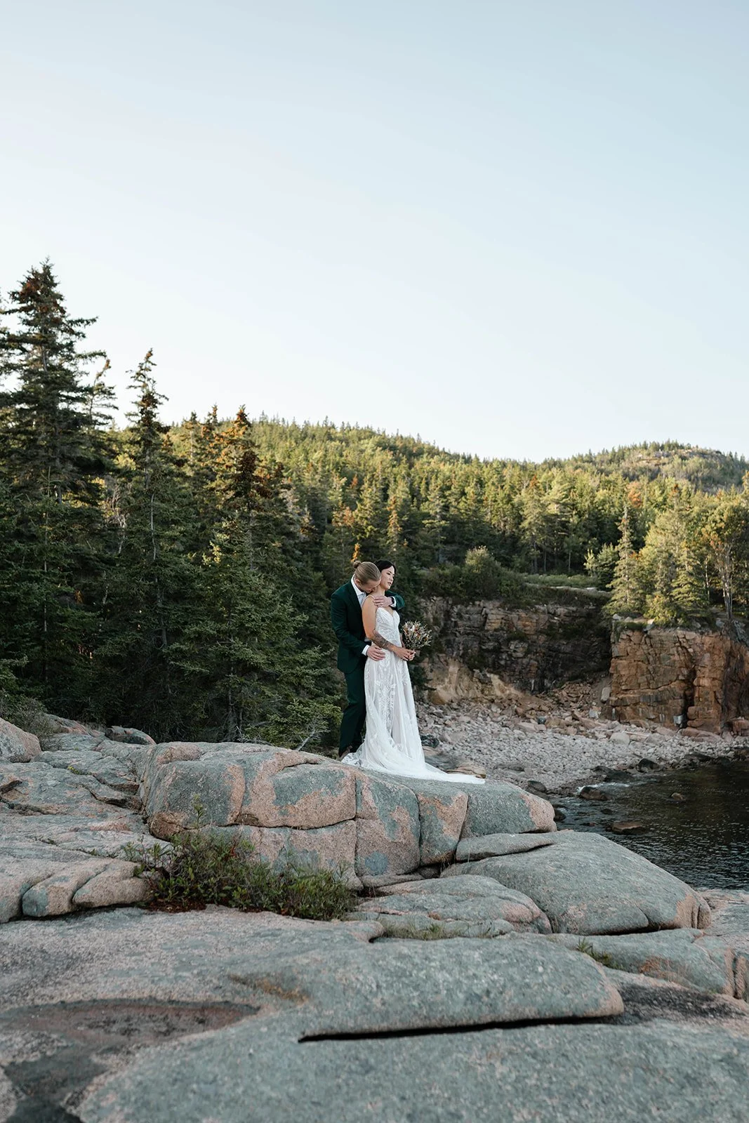 bride and groom standing on a cliff during their acadia elopement