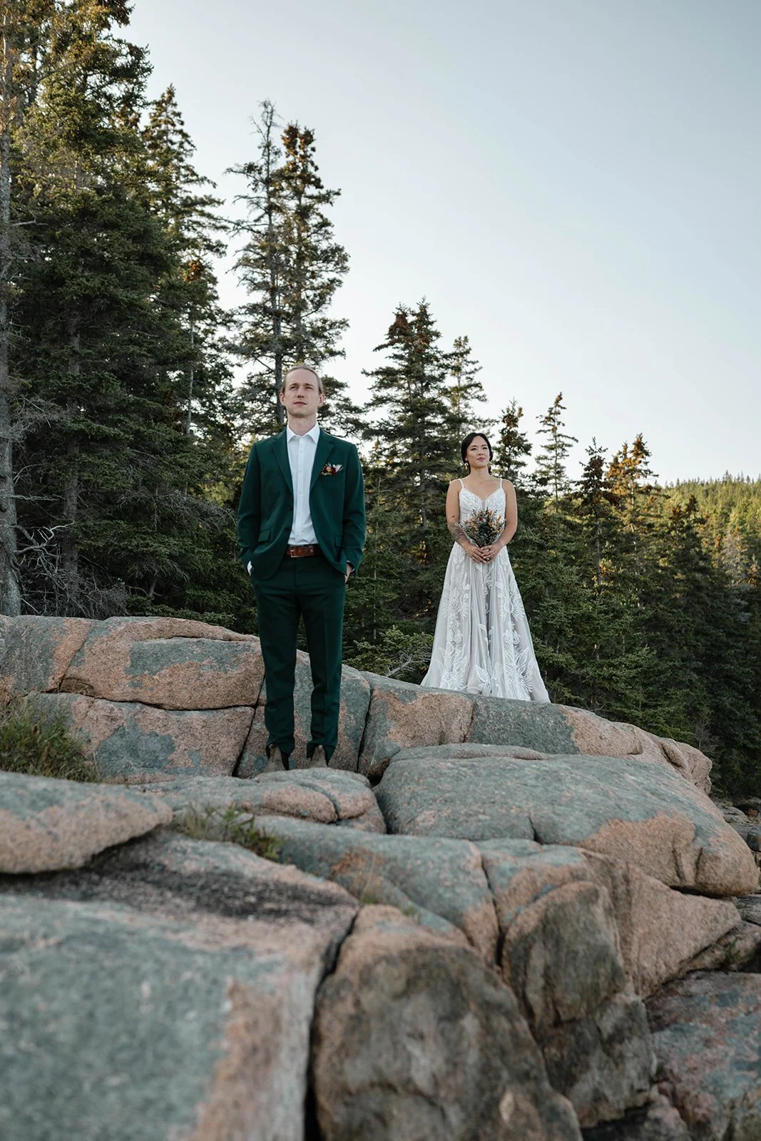 bride and groom standing on a cliff during their acadia elopement