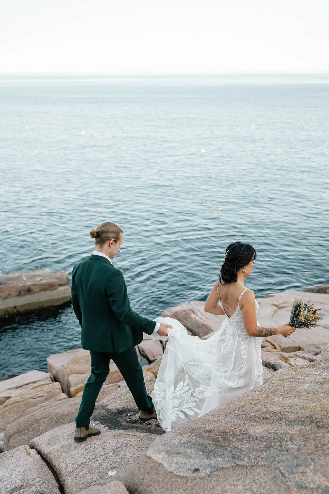 bride and groom walking along a cliff during their acadia elopement