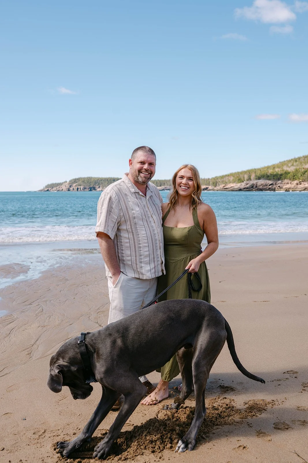 couple and their dog during their engagement session at Sand Beach in Acadia