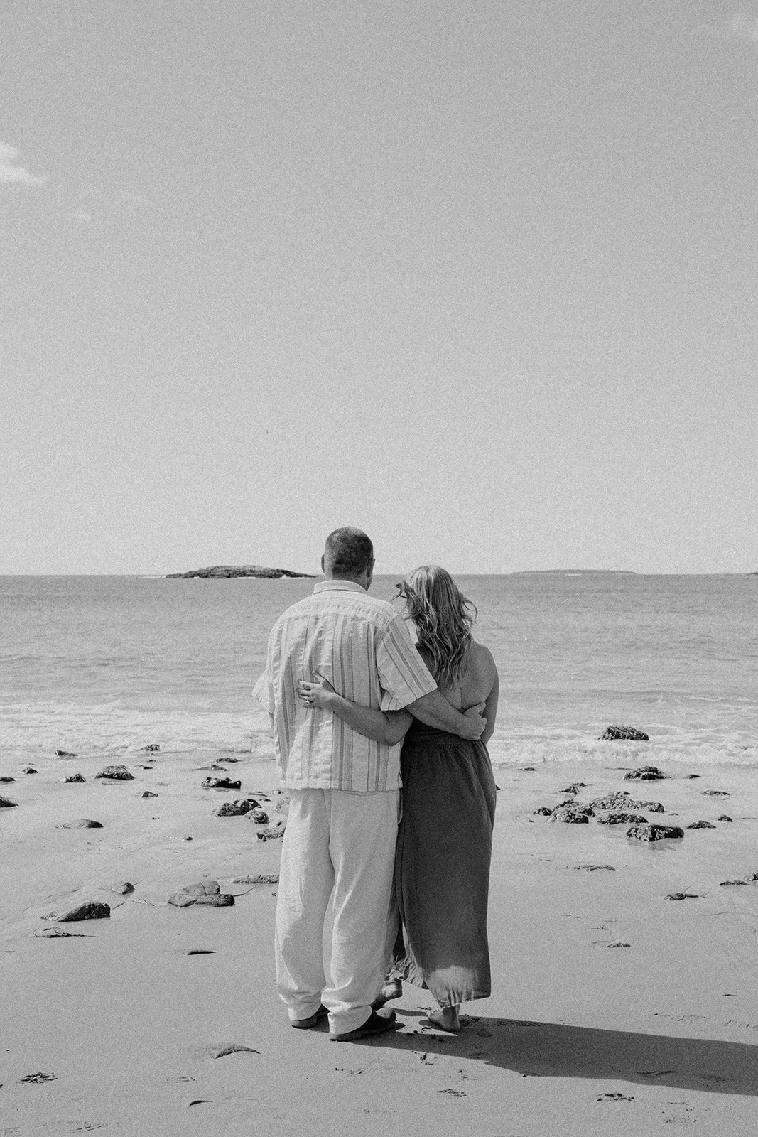 playful couple during their acadia national park engagement photos session at the coast of sand beach