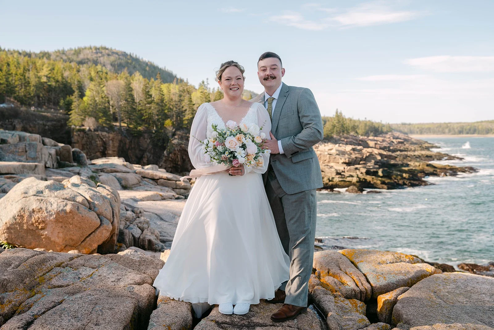 bride and groom on a cliff at monument cove