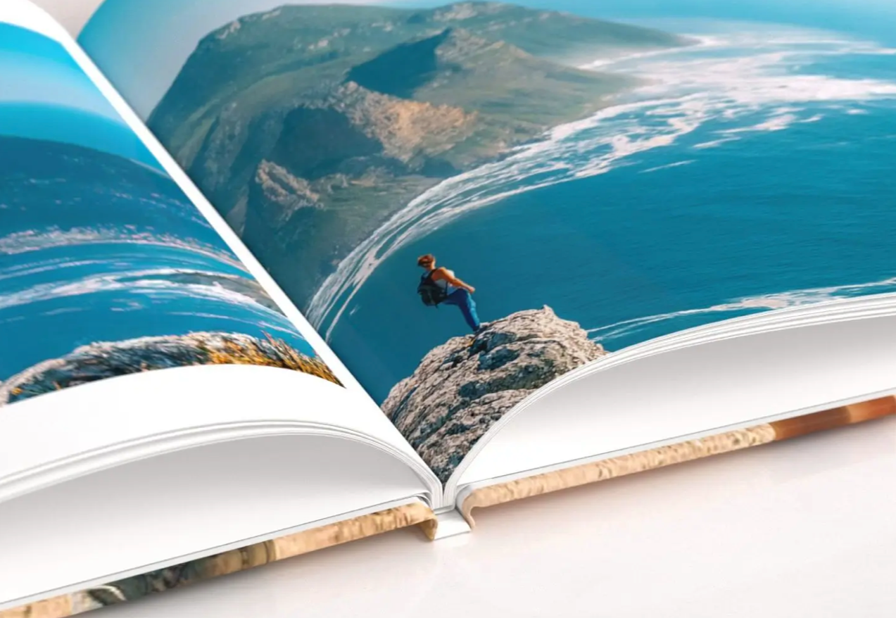 Open photo book with a large mountain wave and a person standing on a rock amid the wave