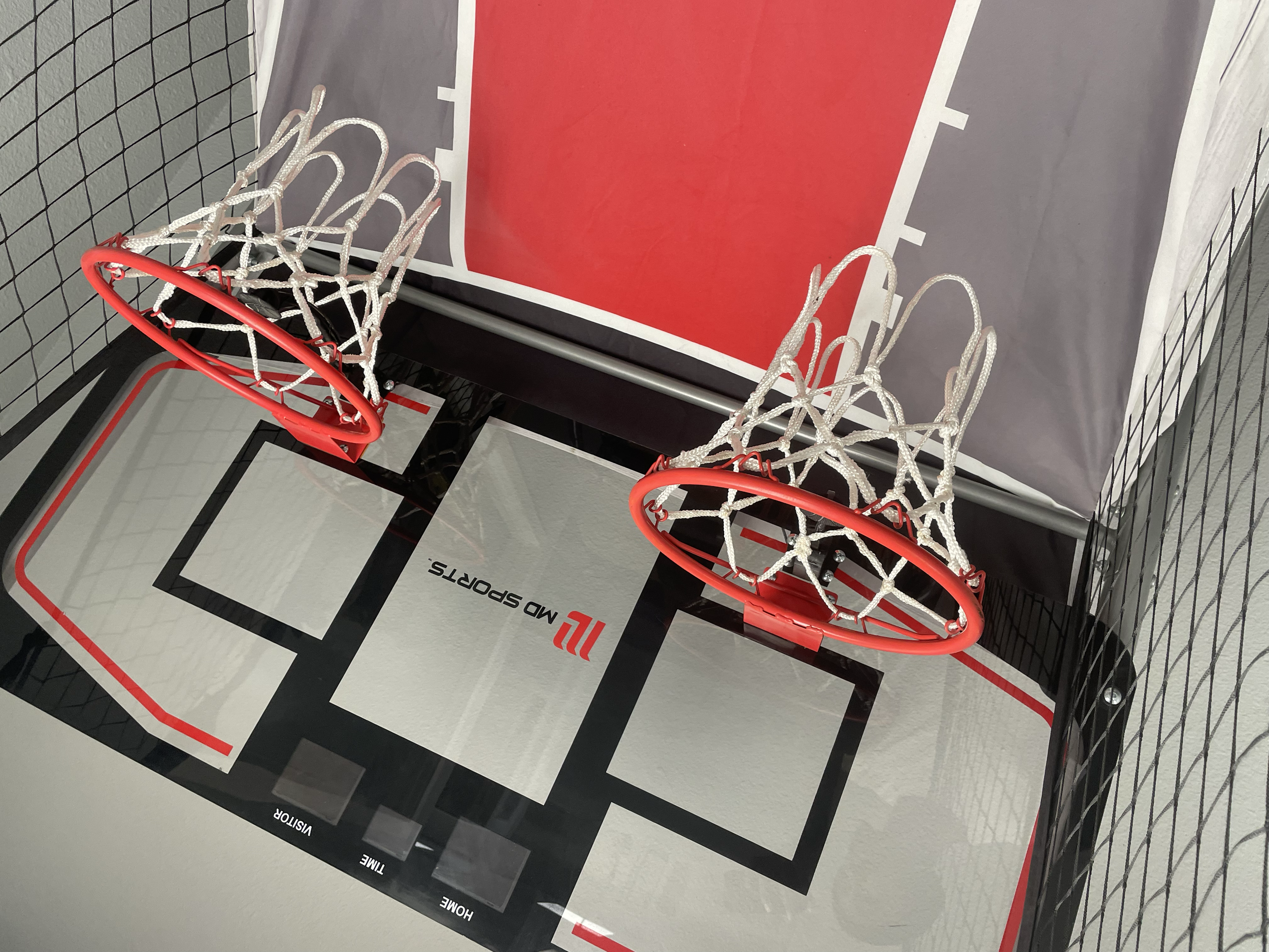 Indoor basketball court with two small basketball hoops and a partial view of a regulation court surface.