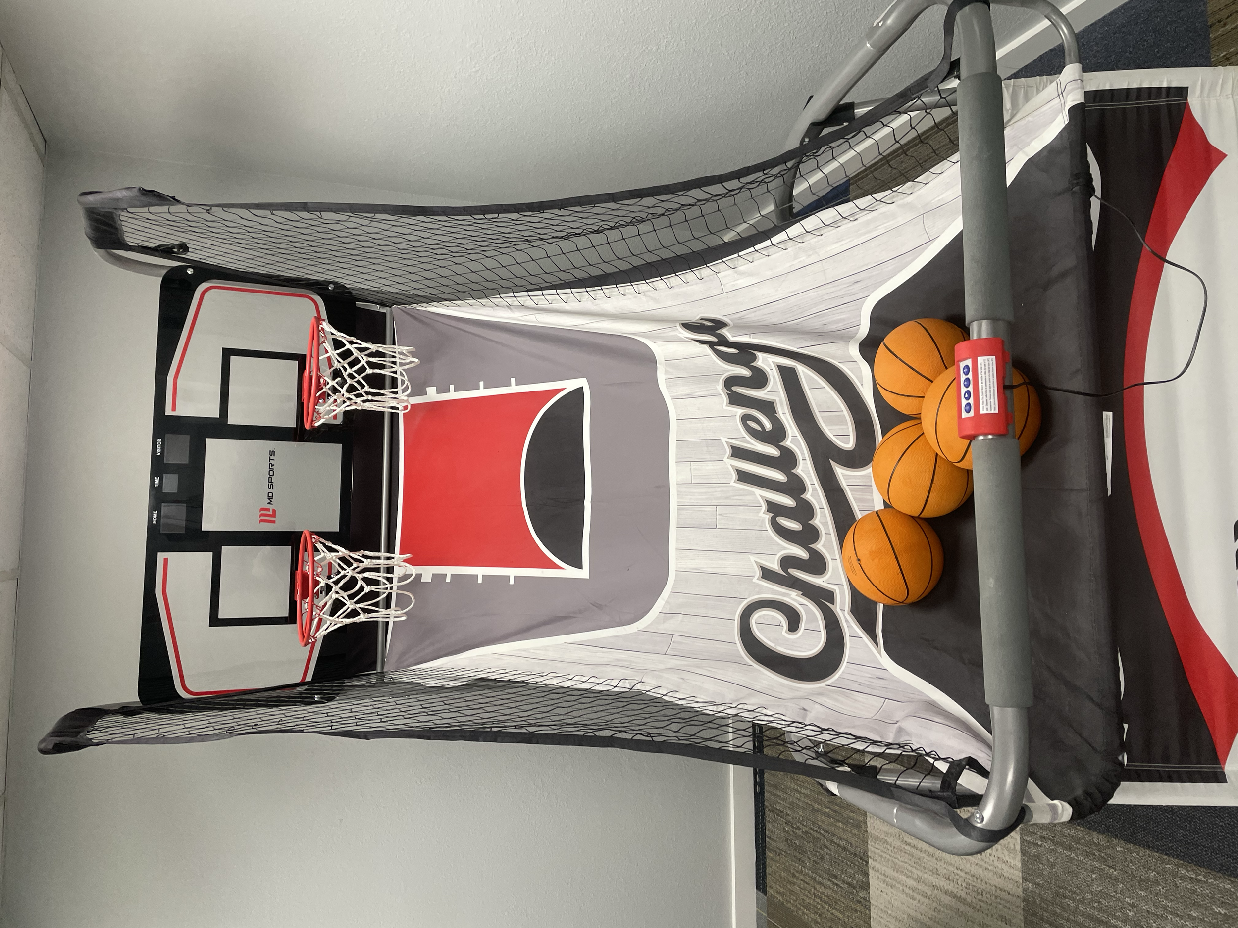 Mini basketball game with two small basketball hoops, a net enclosure, and four basketballs placed on the game structure.