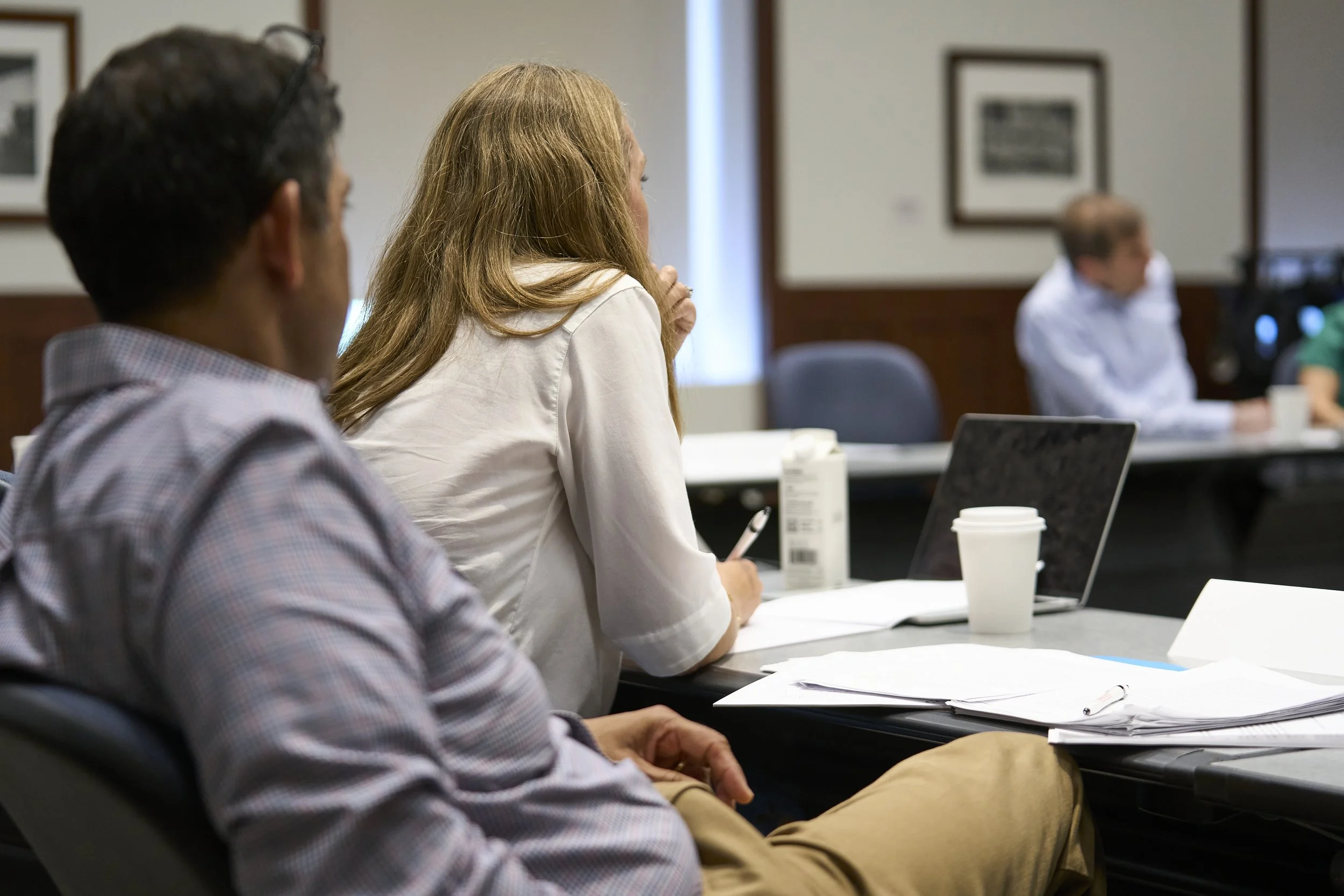 People attending a meeting or conference sitting attentively while listening to the discussion.