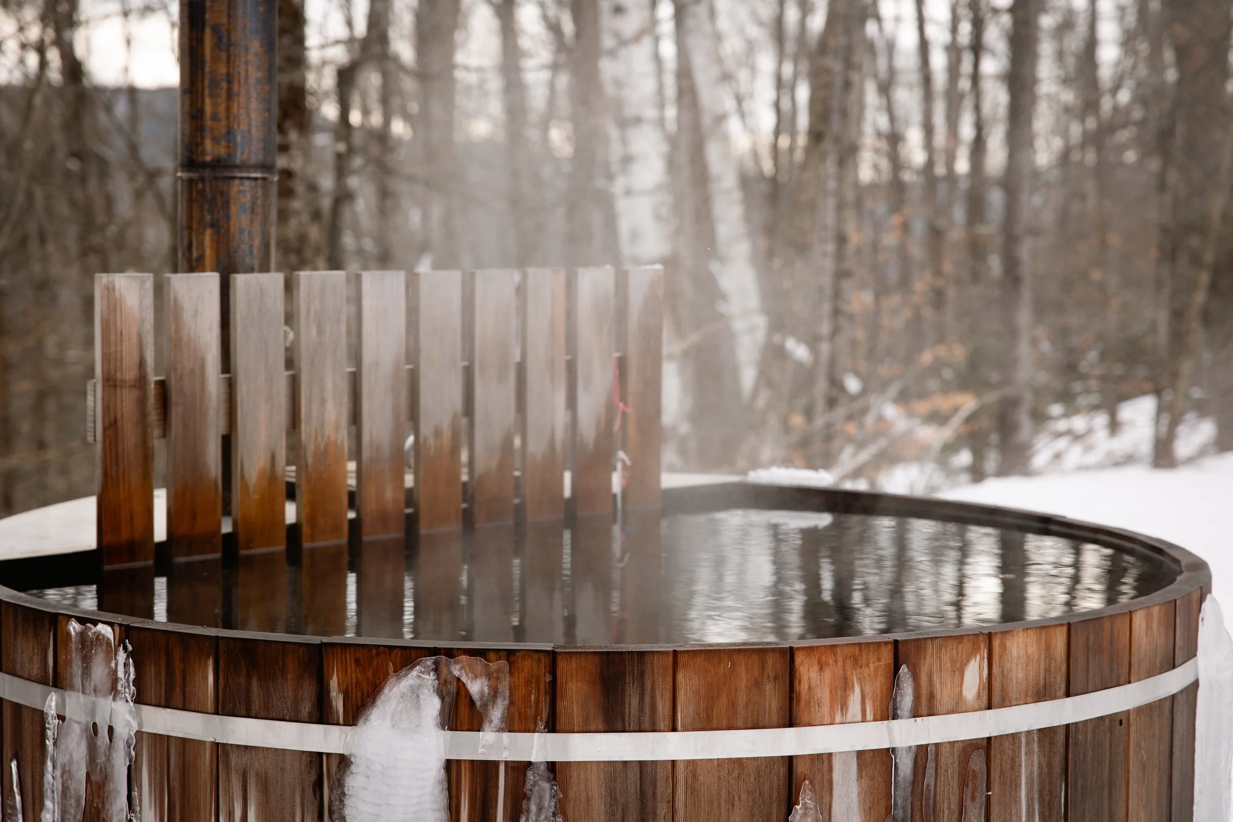 Hot tub made of wood outdoors in a snowy forest