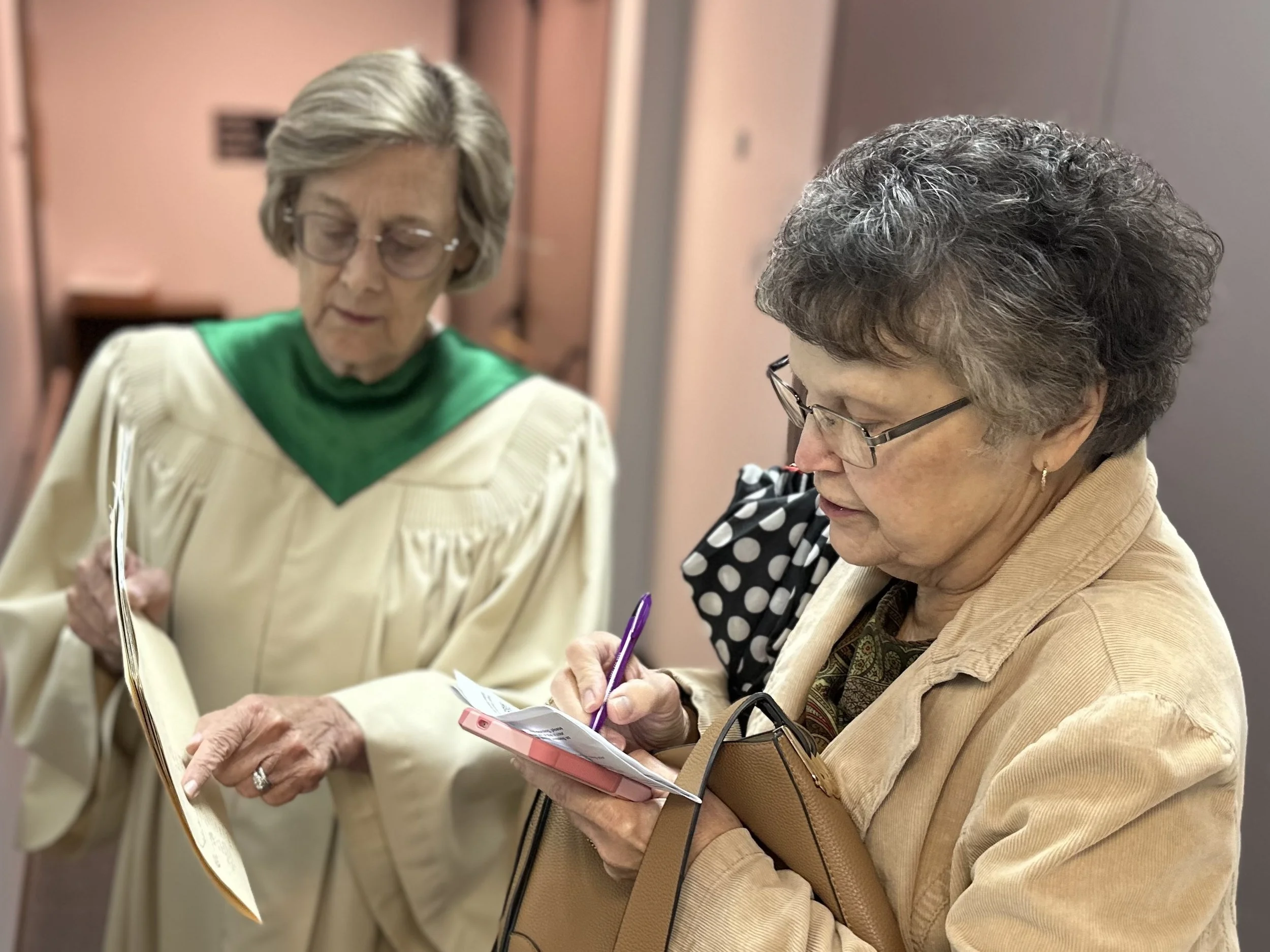 Two women having a conversation and taking notes