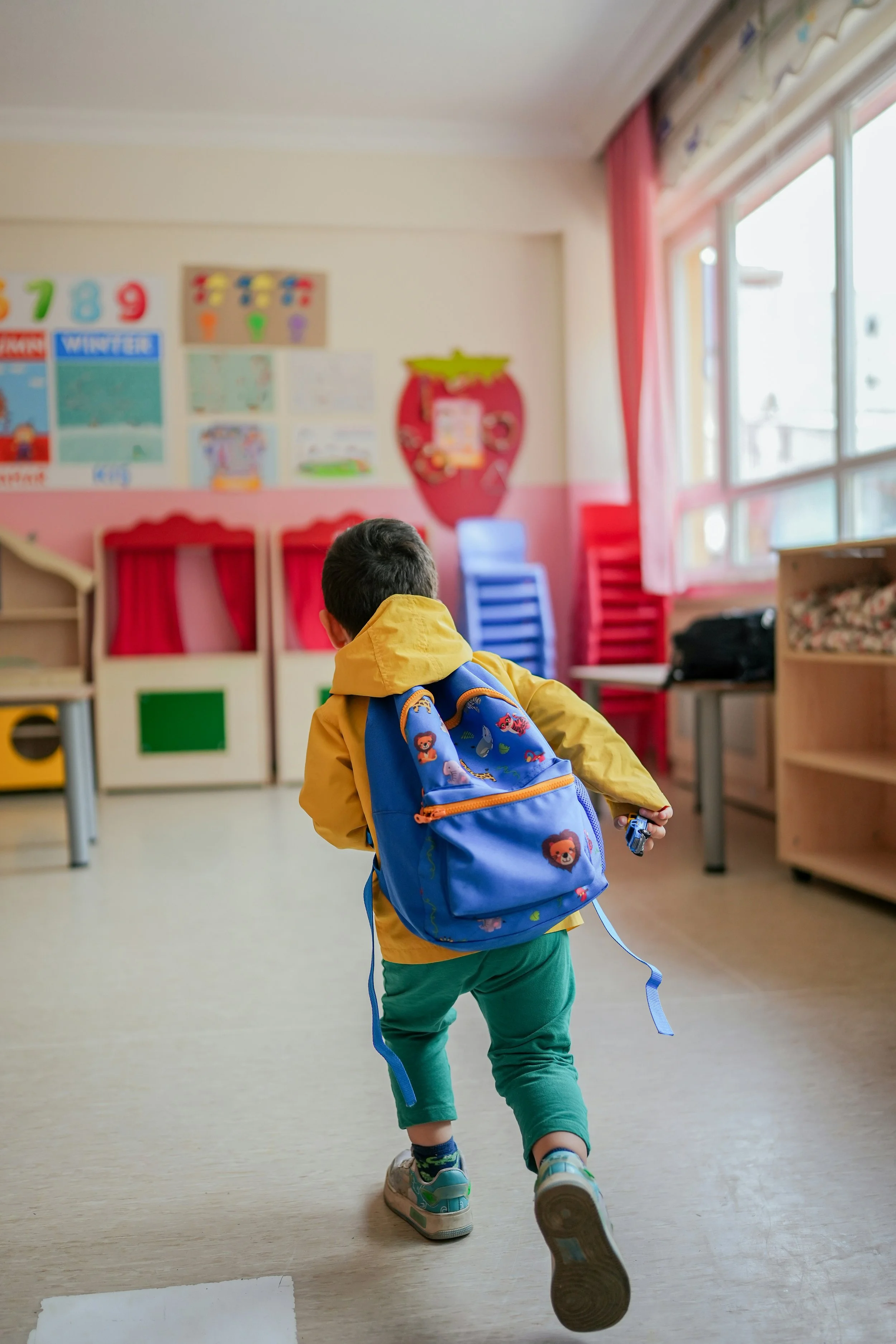 kid running in a classroom wearing his backpack