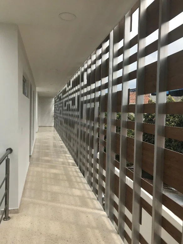 Pasillo exterior con corta soles en madera y estructura de acero como estrategia de protección solar en la Estación de Policía Cero Energía en Florida, Valle, Colombia.