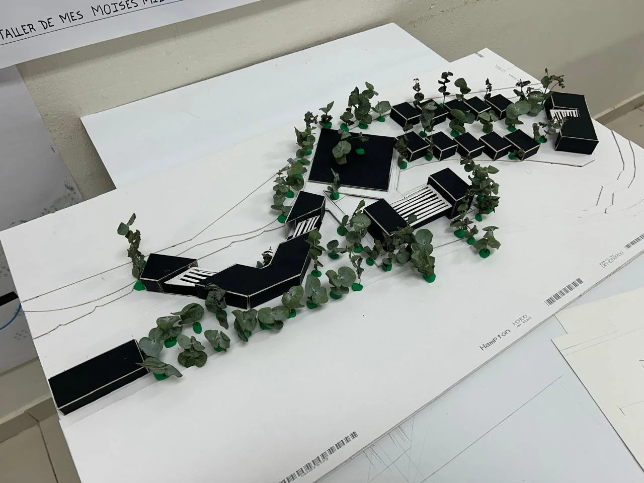 Maqueta de un diseño arquitectónico de edificios con áreas verdes y caminos peatonales en un espacio urbano.