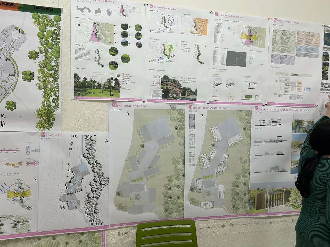 Carteles con planos arquitectónicos y urbanísticos en una pared, incluyendo mapas, diagramas, y diseños de edificios y áreas verdes, en un entorno de presentación o exposición.