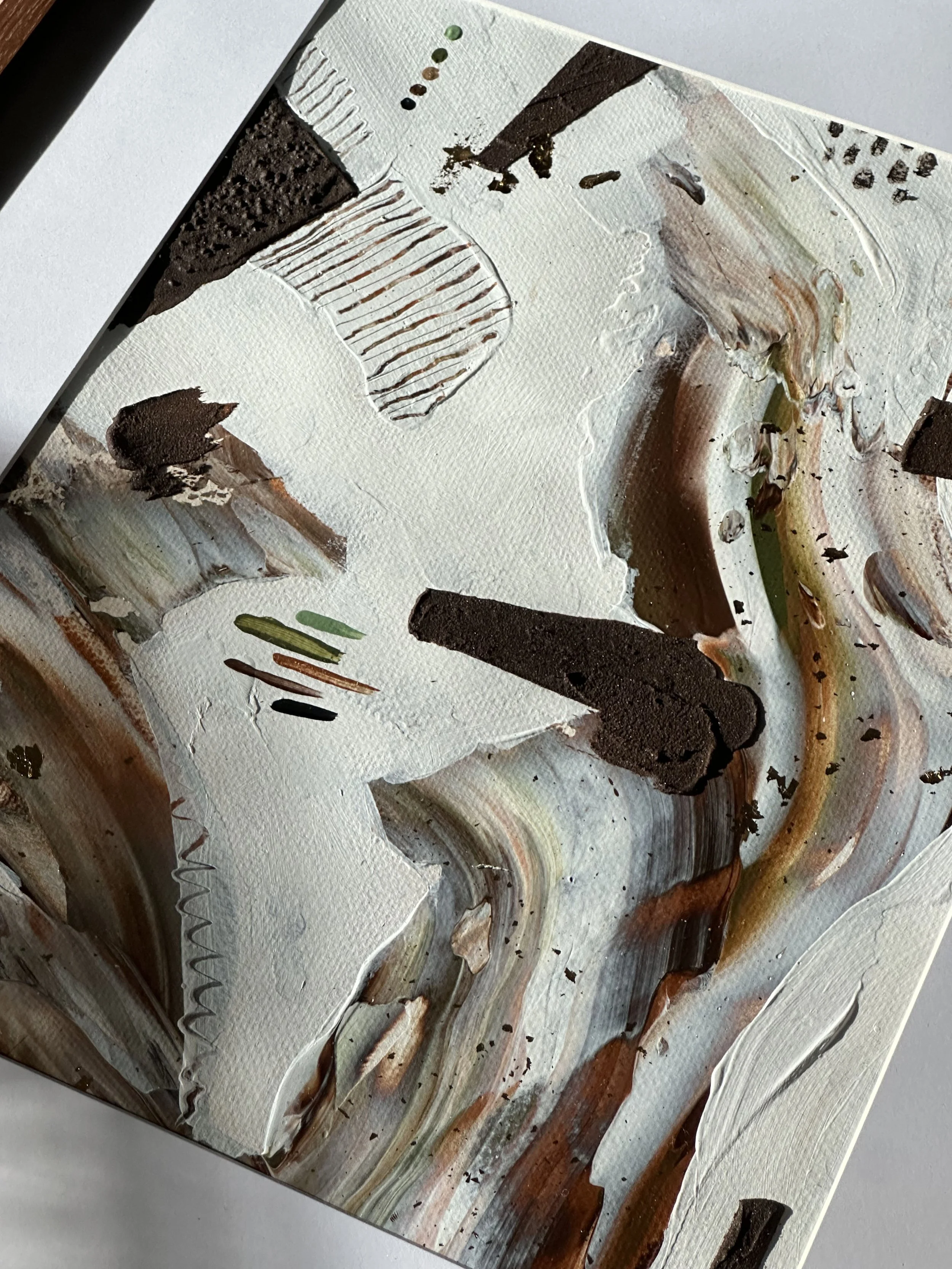 Close-up of an abstract painting with textured white and earthy tones, featuring bold black accents, varied brushstrokes, and layered paint.