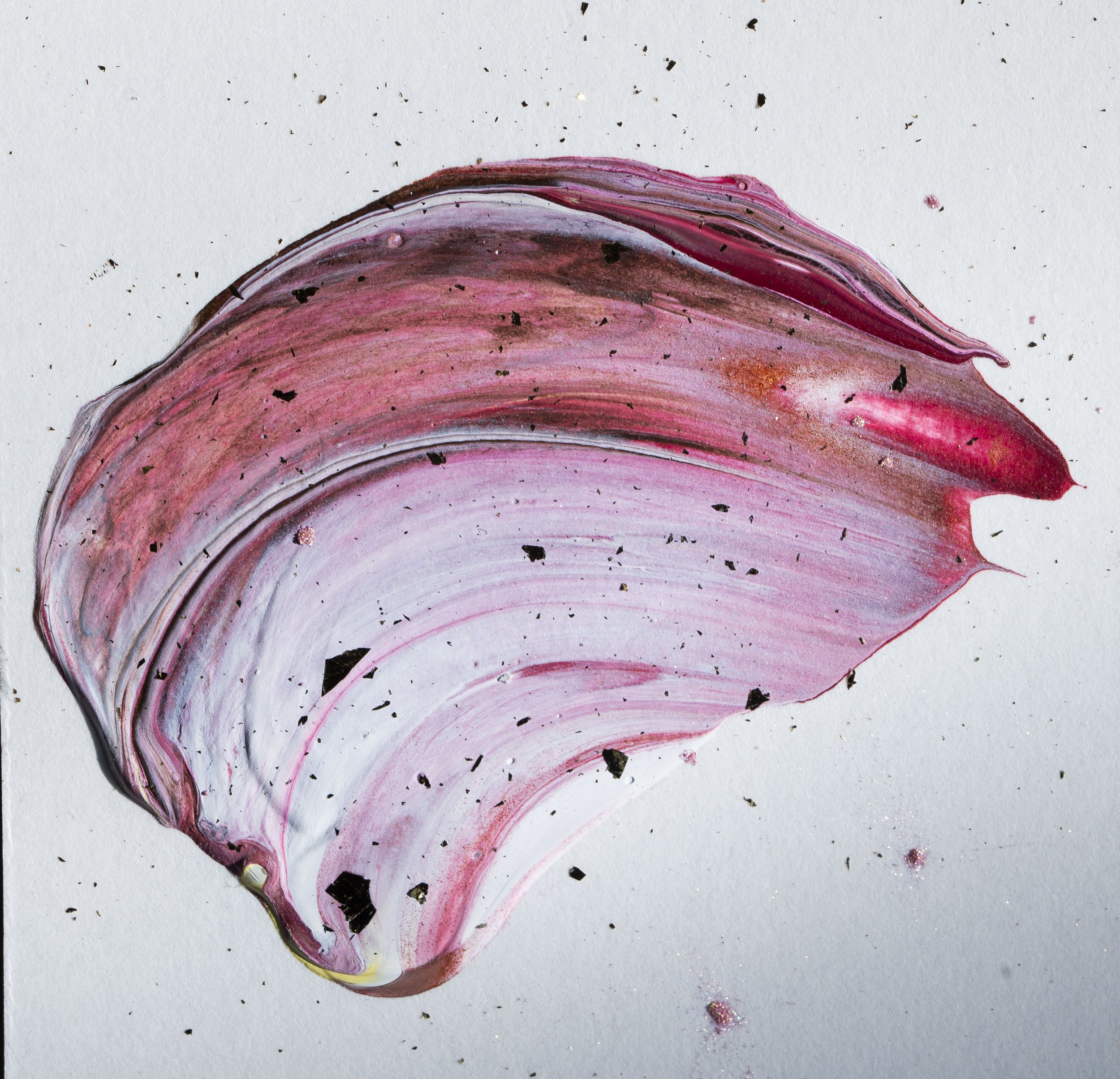 Pink and white paint swirled on white background with small black and pink specks.