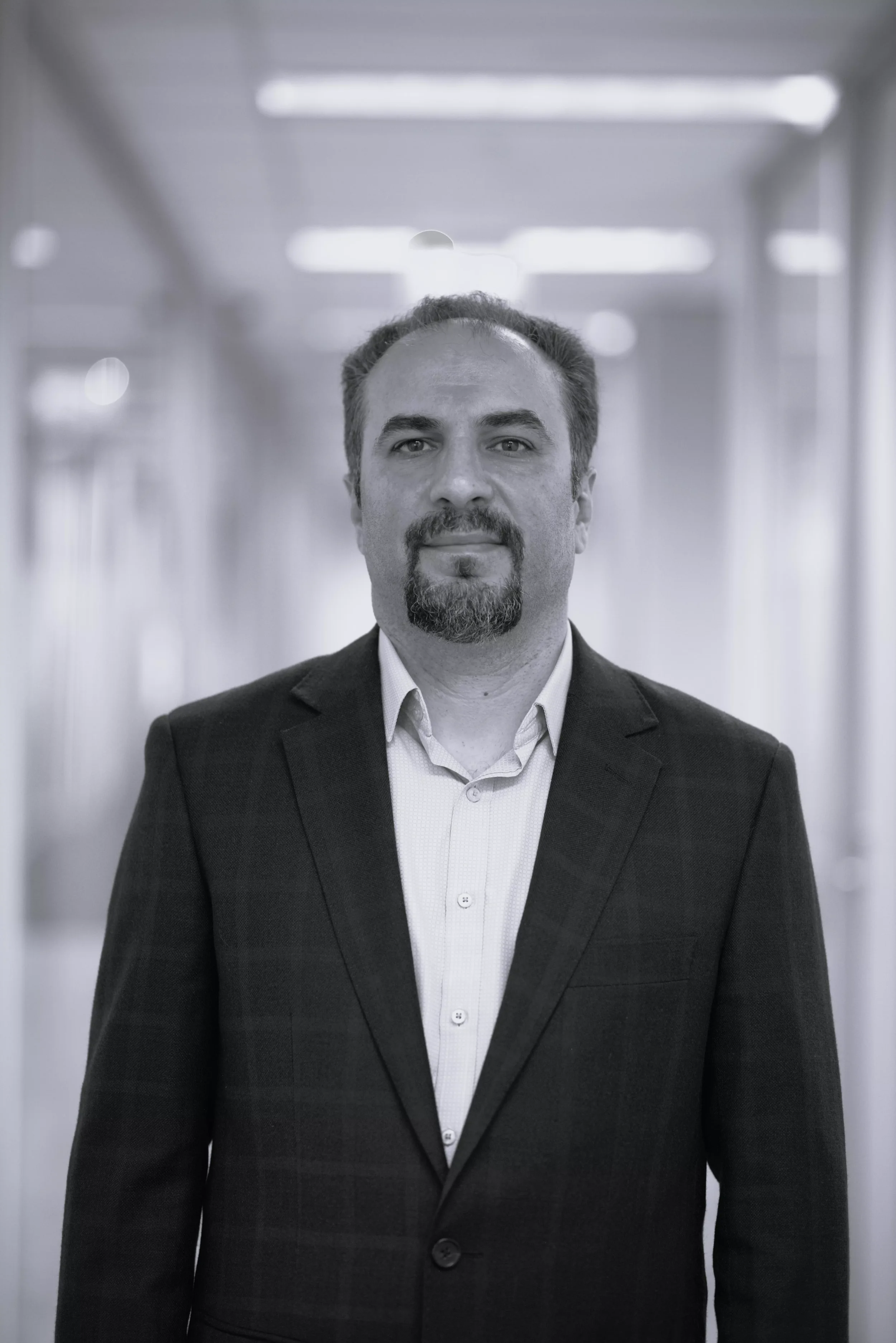 Man in business suit standing in a blurred hallway.