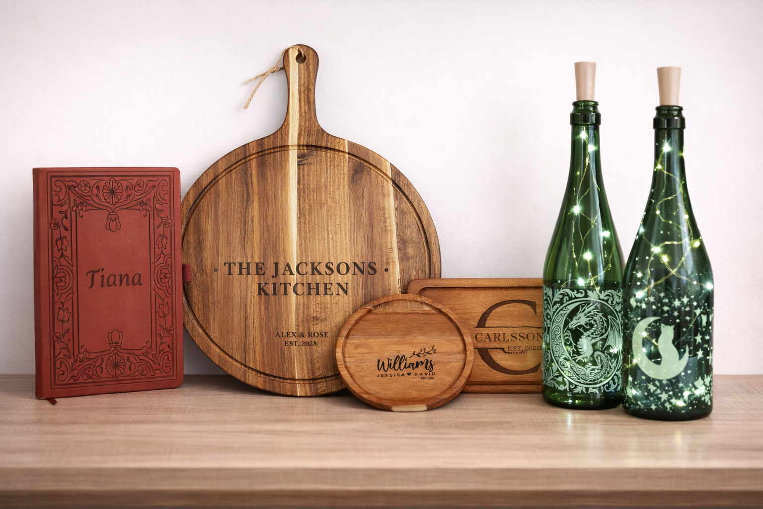 laser engraved items that include a brown journal, charcuterie boards in 3 sizes, and 2 engraved wine bottles with fairly lights inside.