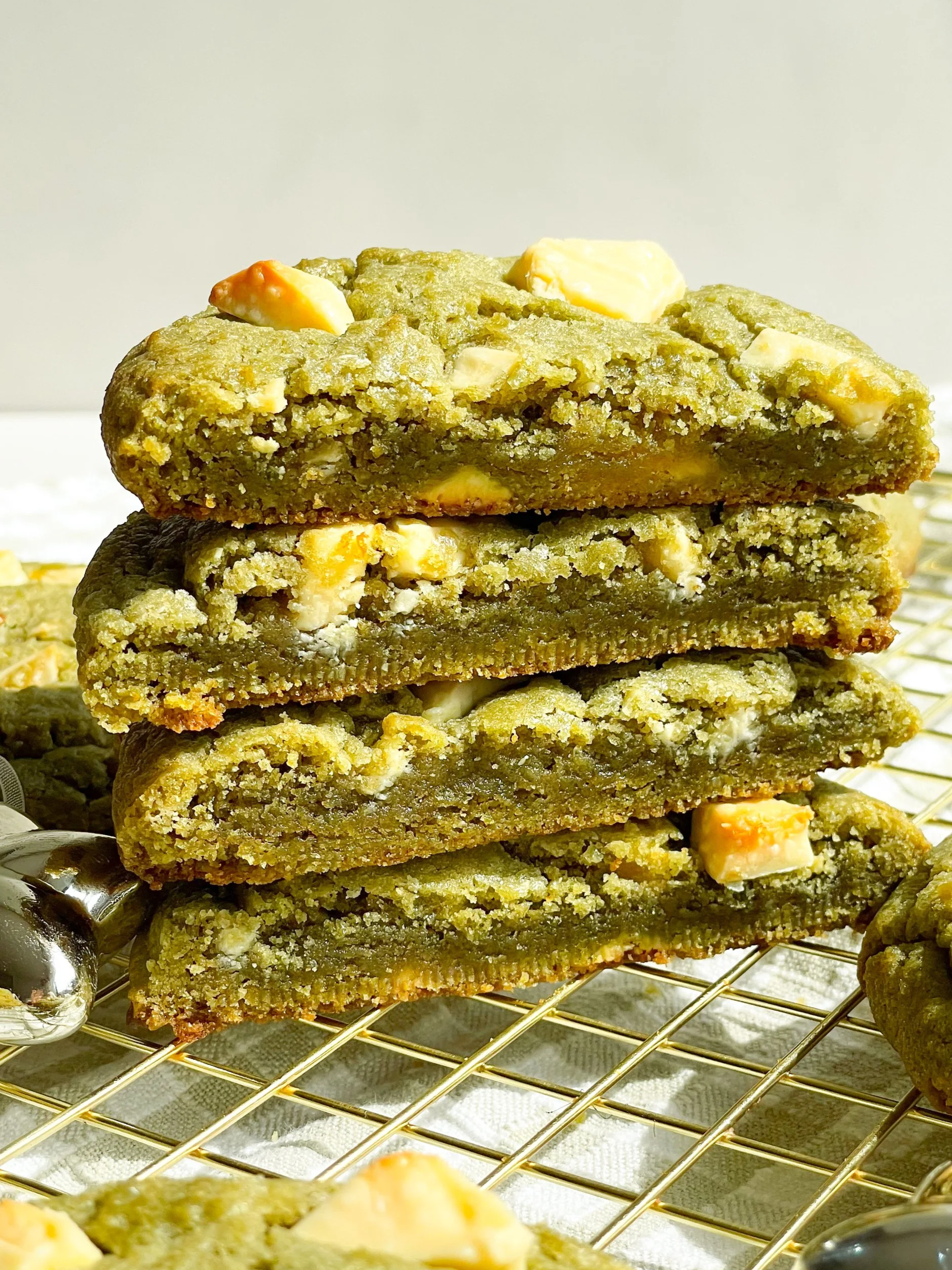Stacked green cookie bars with white chocolate chunks on a cooling rack.