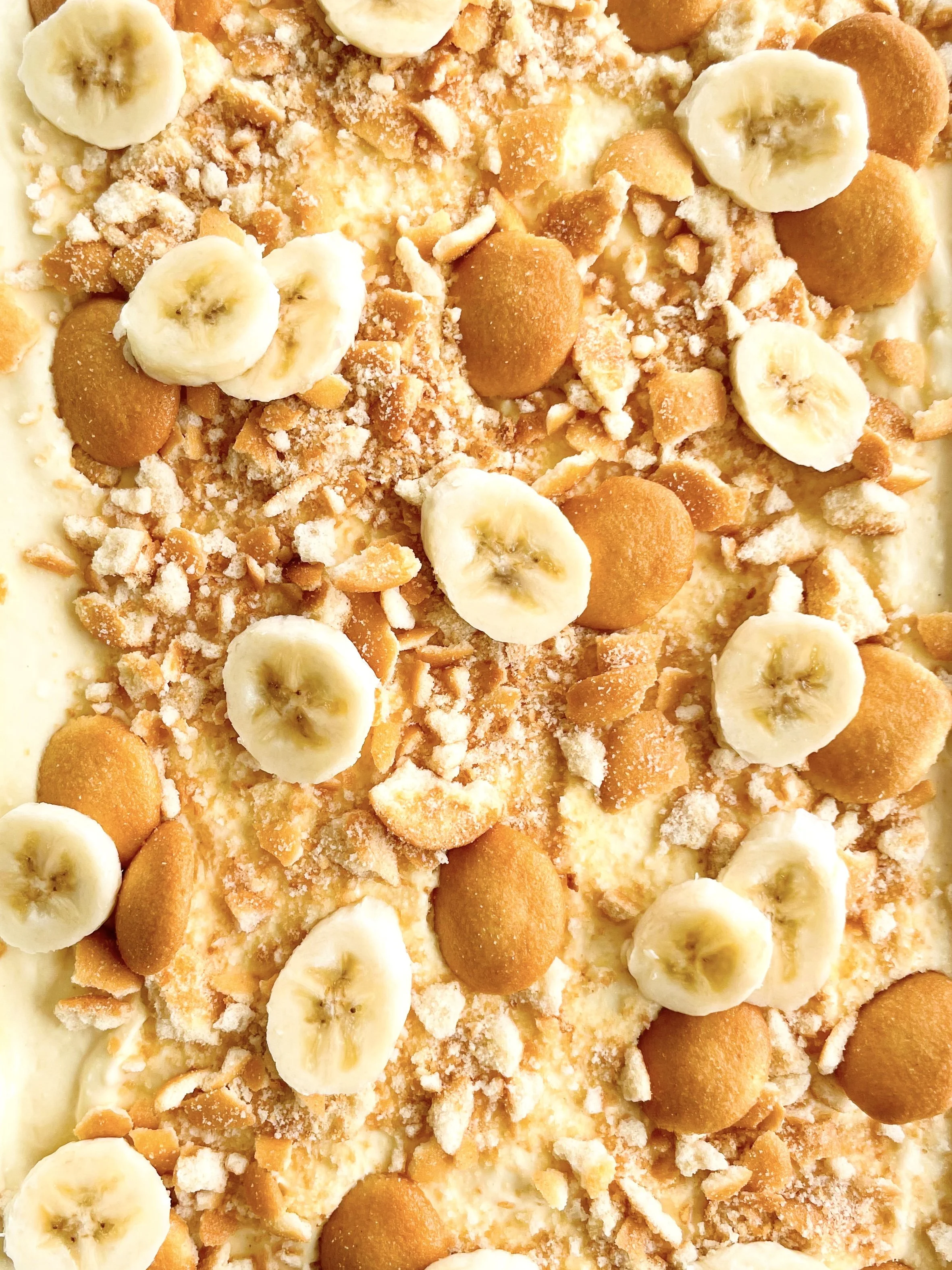 Close-up of a banana cheesecake topped with banana slices, crushed cookies, and crumbled toppings.