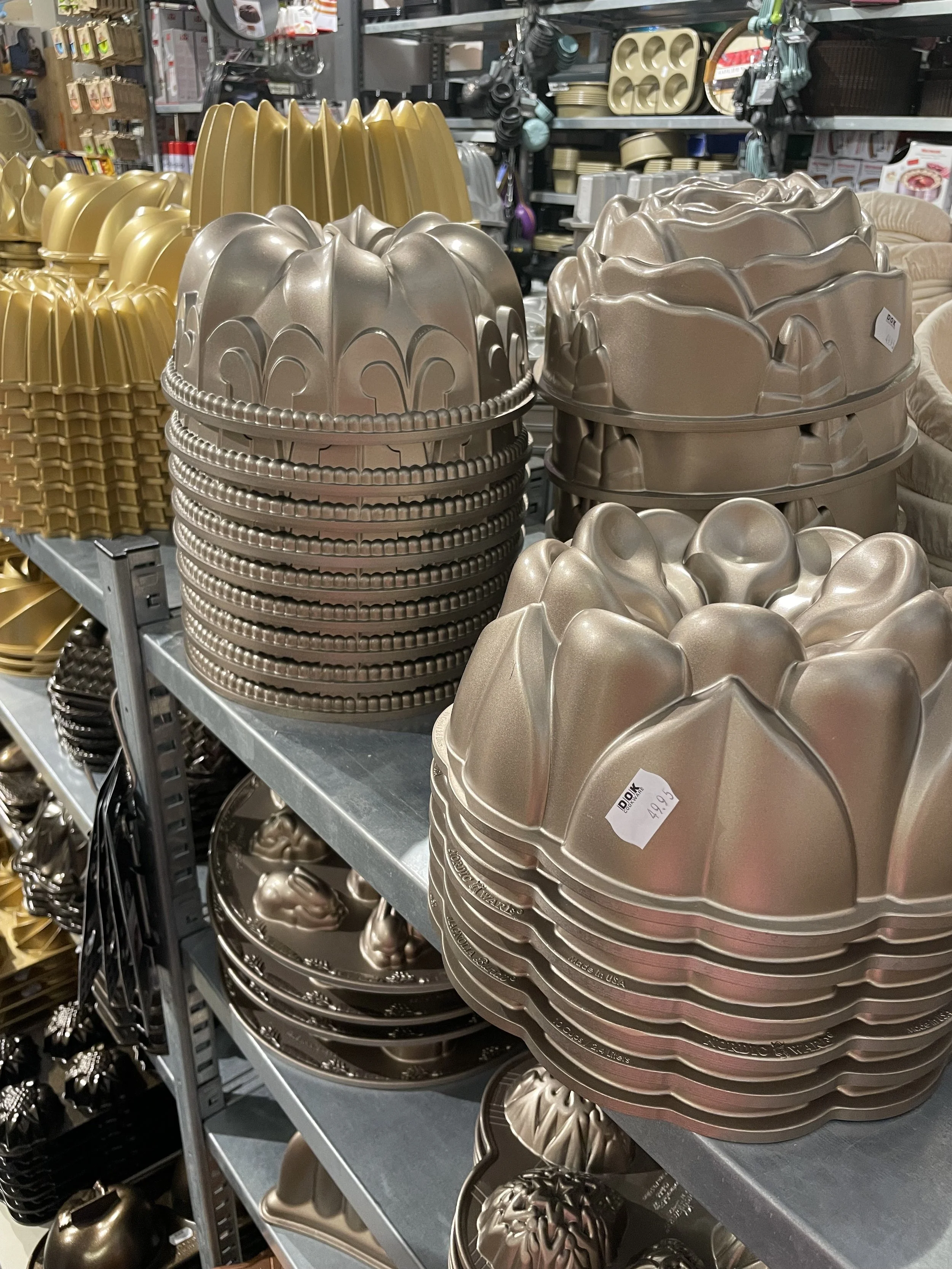 A store shelf displaying various bundt pans in gold and bronze colors.