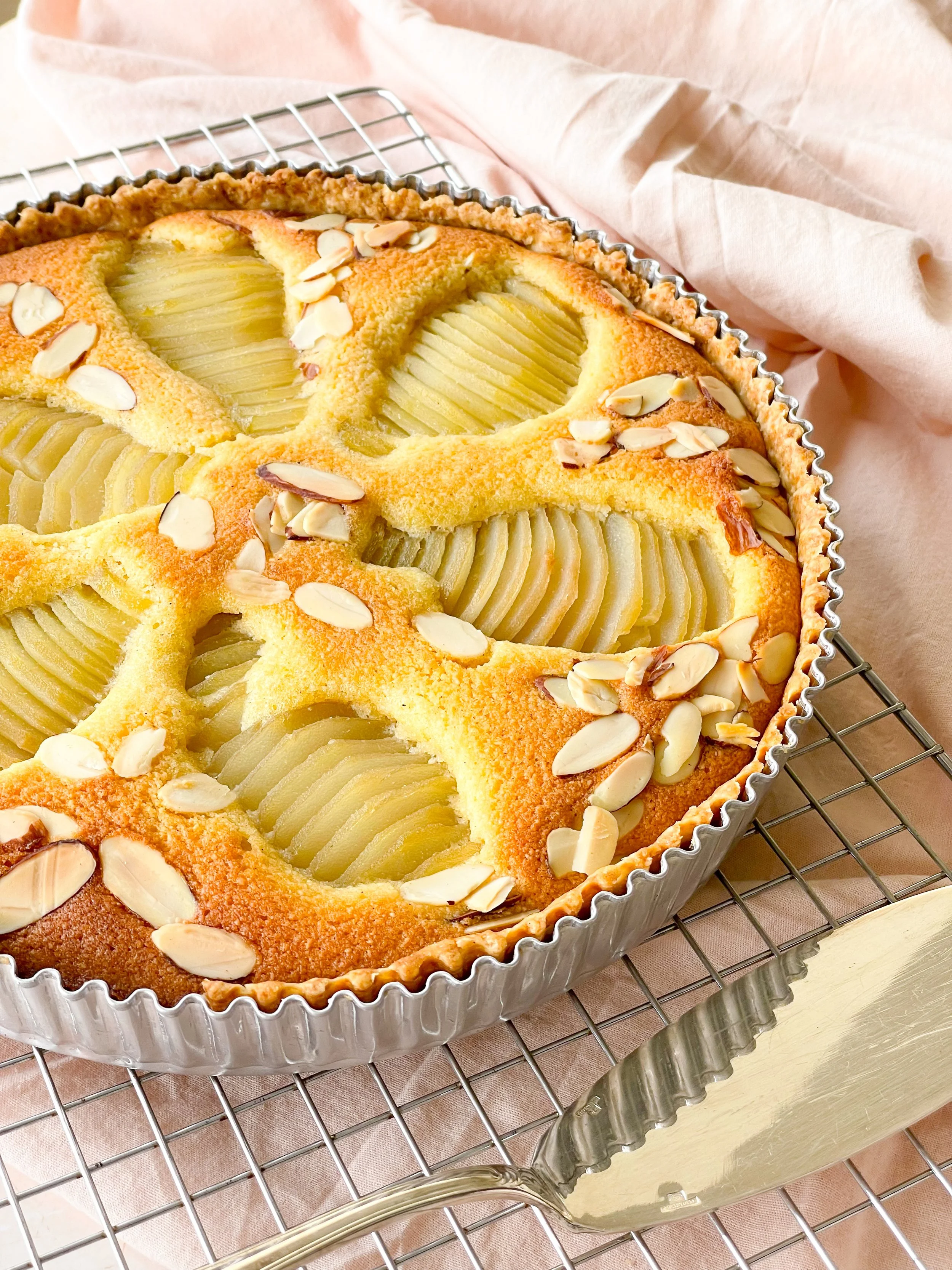 Peach almond pie with sliced peaches and almond slices on top in a fluted pie crust.