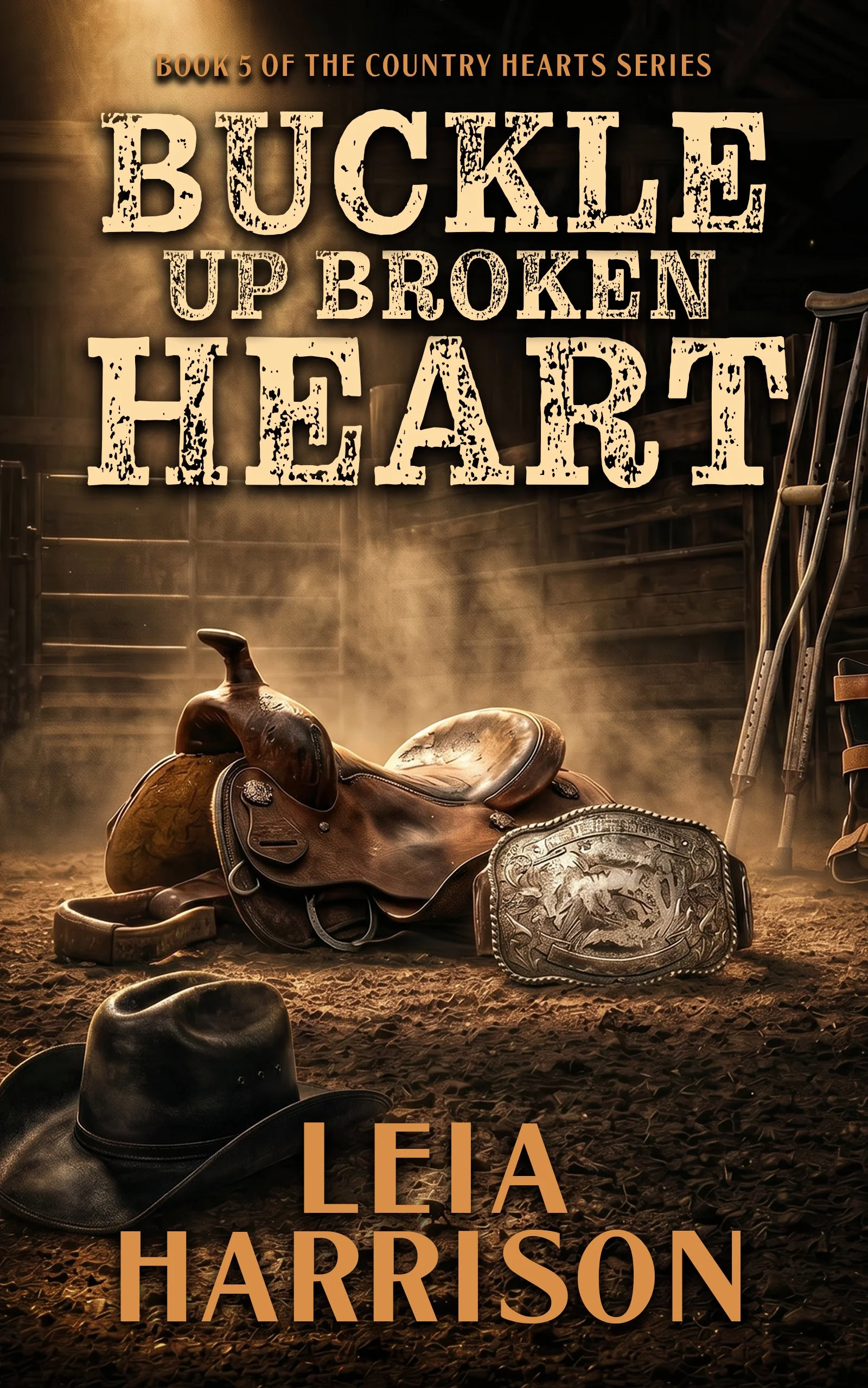A western-themed book cover featuring a saddle, a cowboy hat, chaps, and other western gear on a dirt floor. The background exhibits a barn or stable setting. The title reads 'Buckle Up Broken Heart' and the author is Leah Harrison, with the series indicating it is the fifth book.