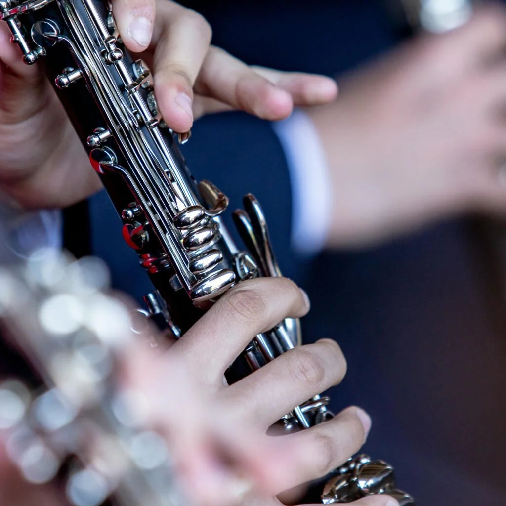 Close-up of a person's hand playing a black and silver flute.