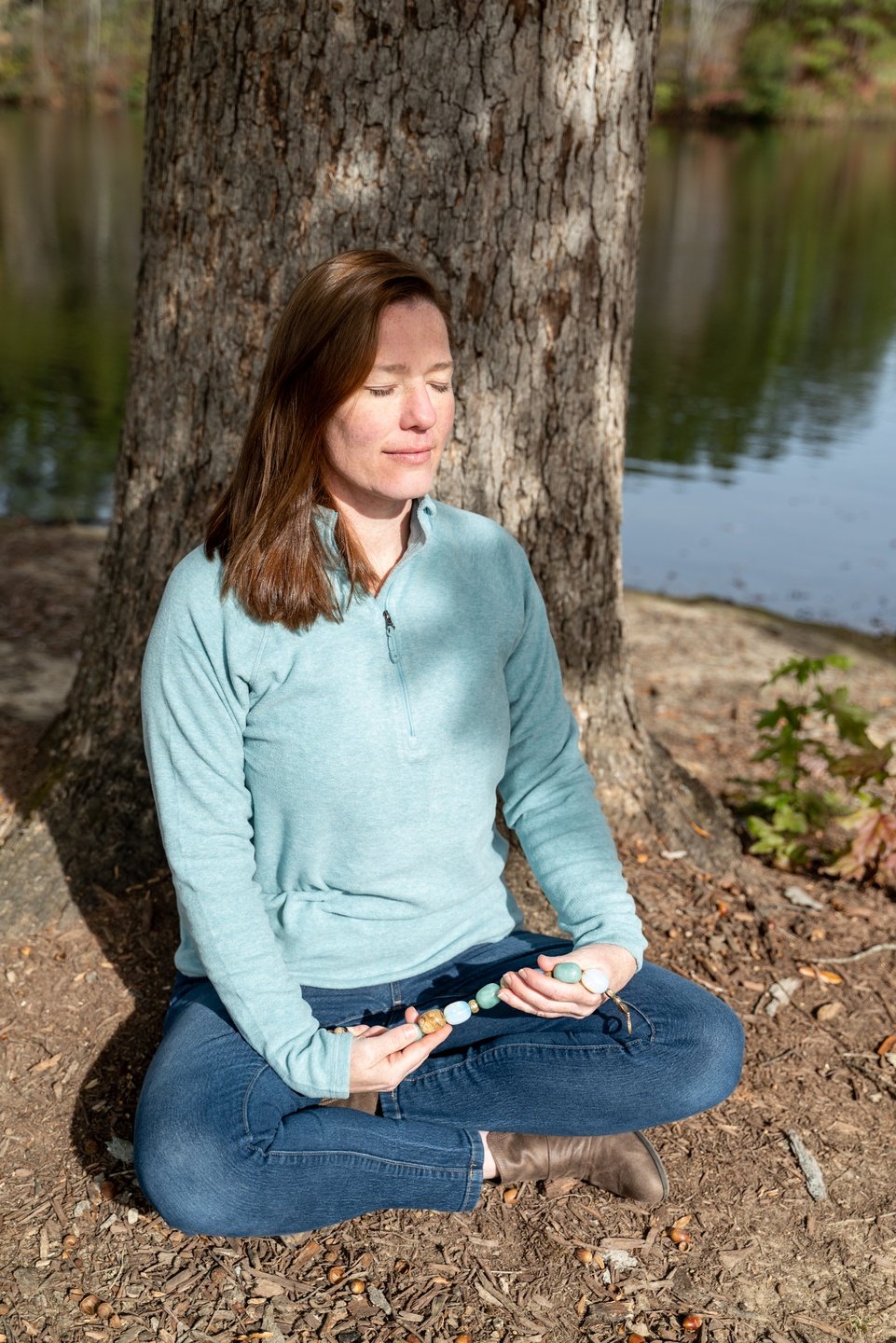 Past Life Regression and Life Between Lives Hypnotherapist Jen Catlin sitting with back against a tree in a park meditating