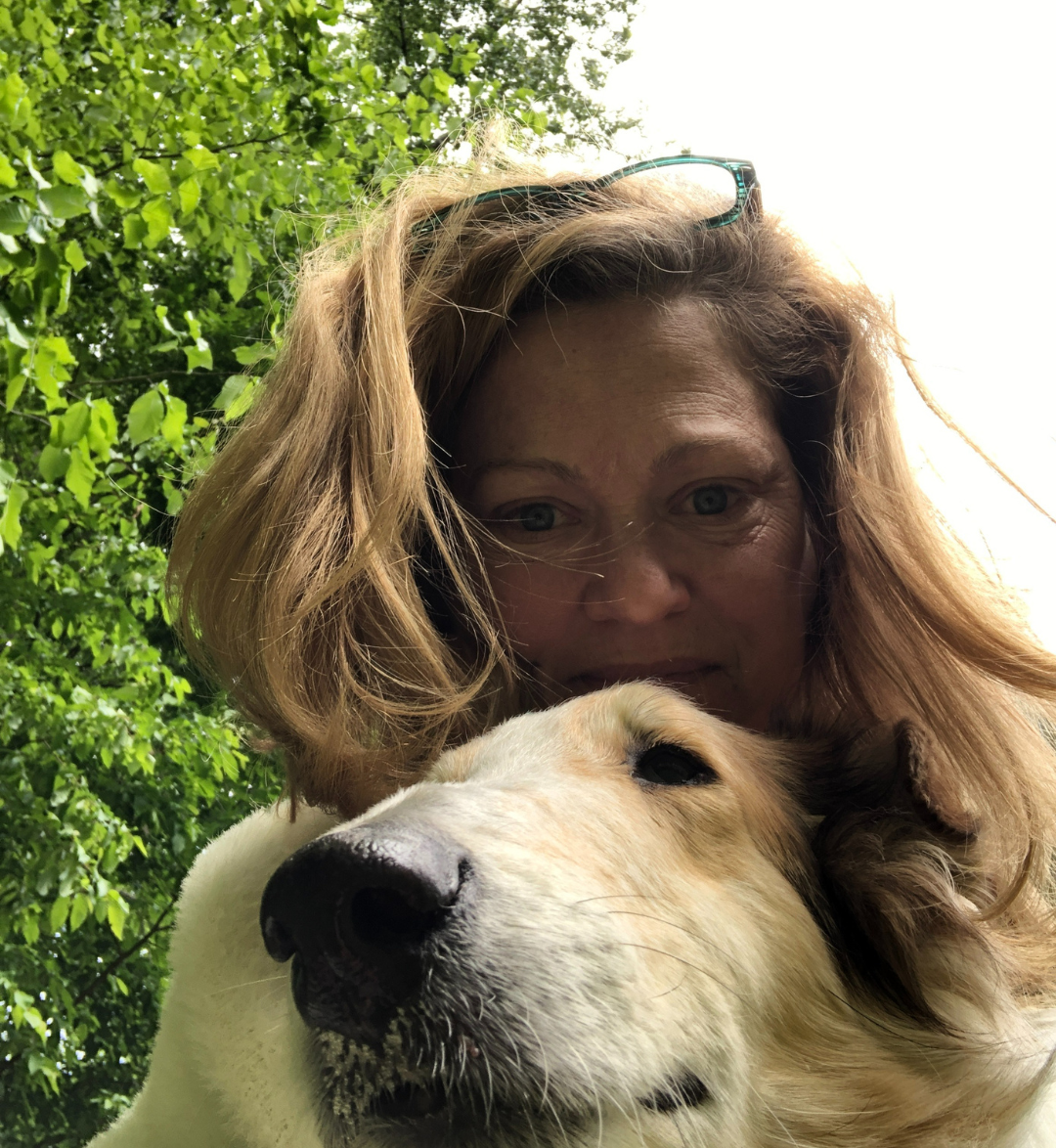 A hypnotherapist and user of the past life regression preparation kit that Jennifer Catlin created who took a selfie with her dog outdoors among green trees.