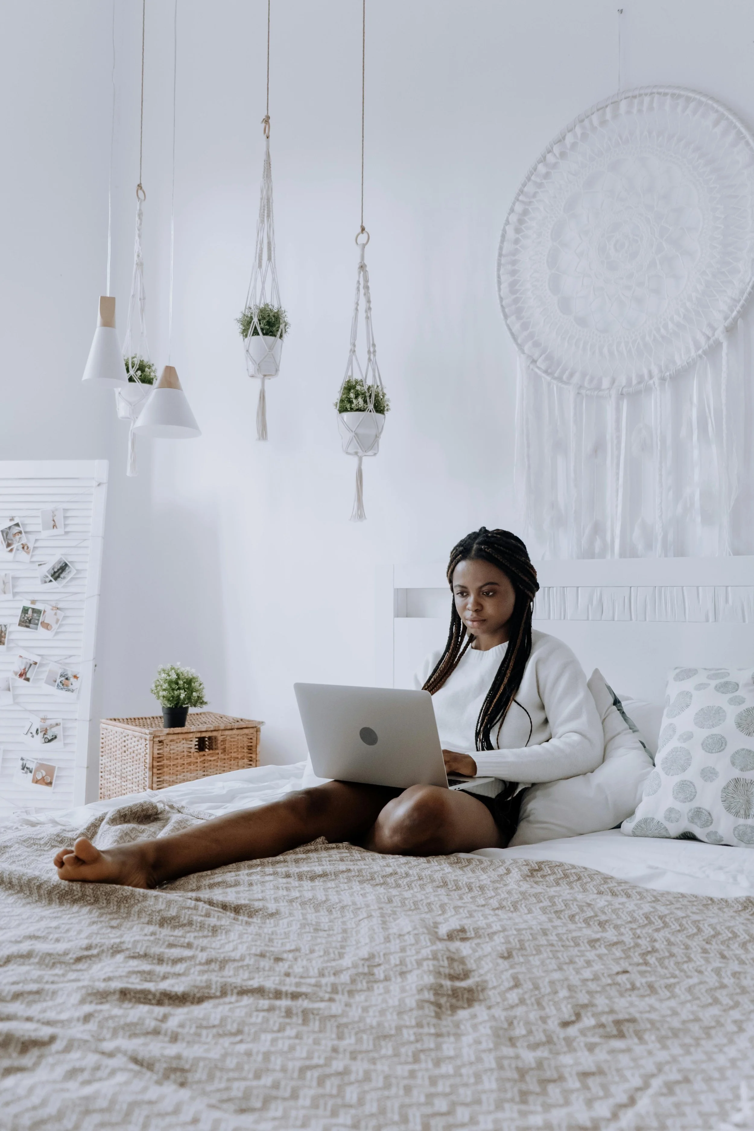 Young woman sitting on a bed with her laptop in an online hypnotherapy certification training