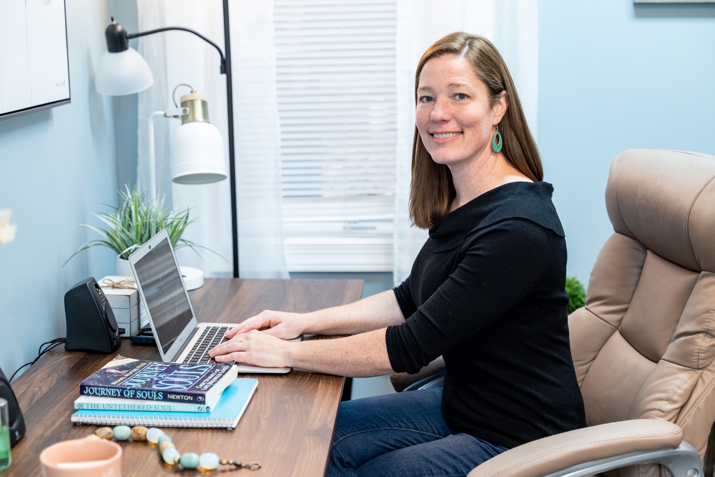 Hypnotherapist and hypnotherapy certification instructor Jen Catlin sitting at her desk in her office working on her hypnotherapy certification training