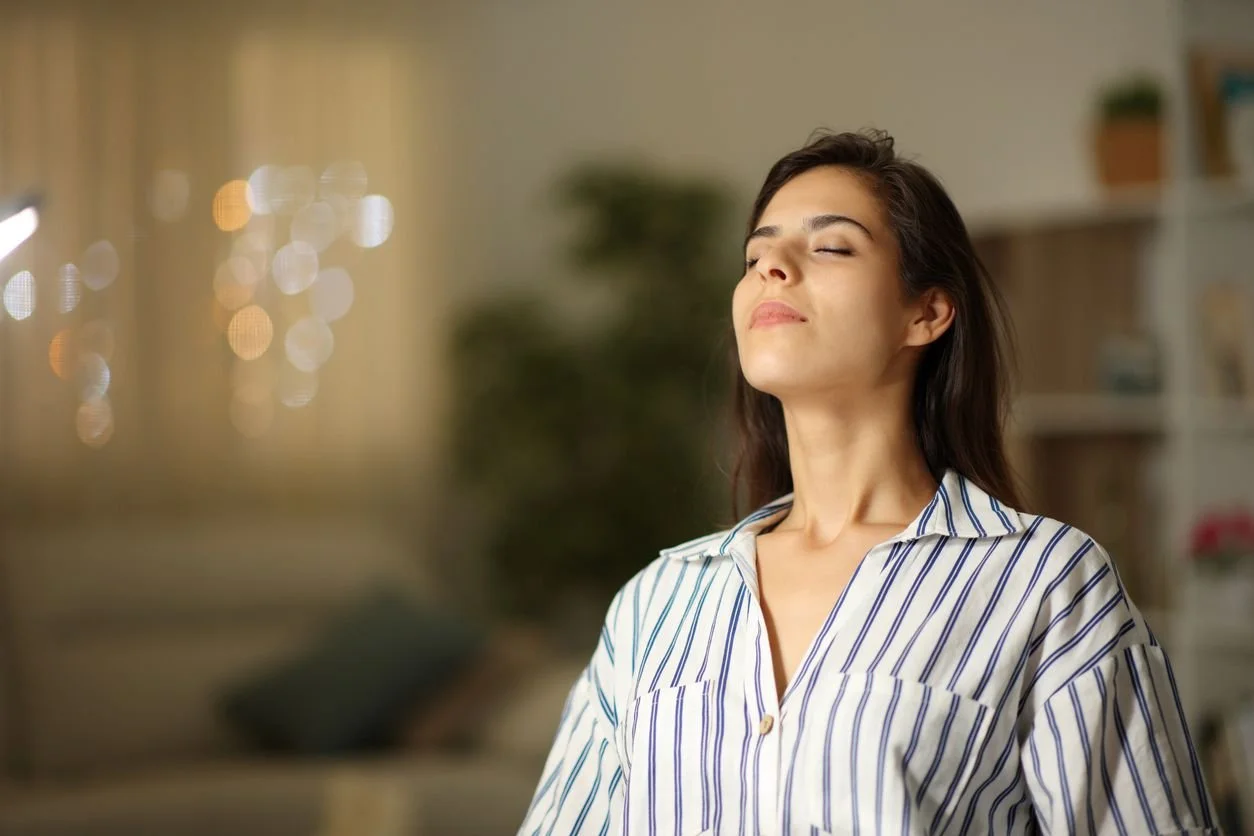 Woman with eyes closed, meditating or experiencing guided hypnosis in a room