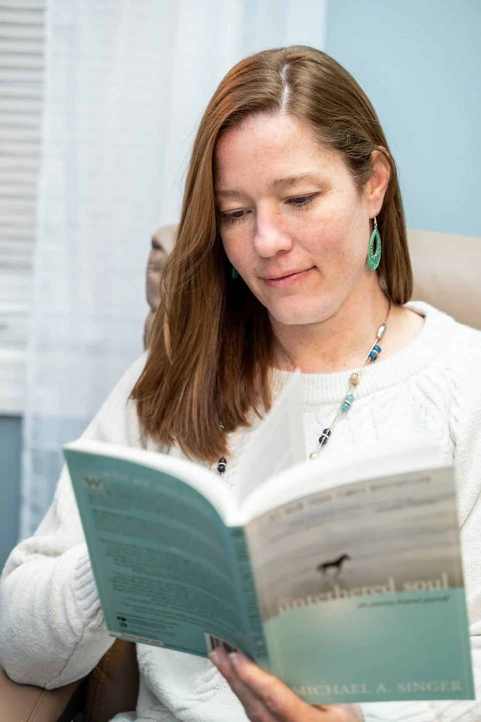 past life regression and Life Between Lives hypnotherapist Jennifer Catlin reading a book in her Cary, NC office