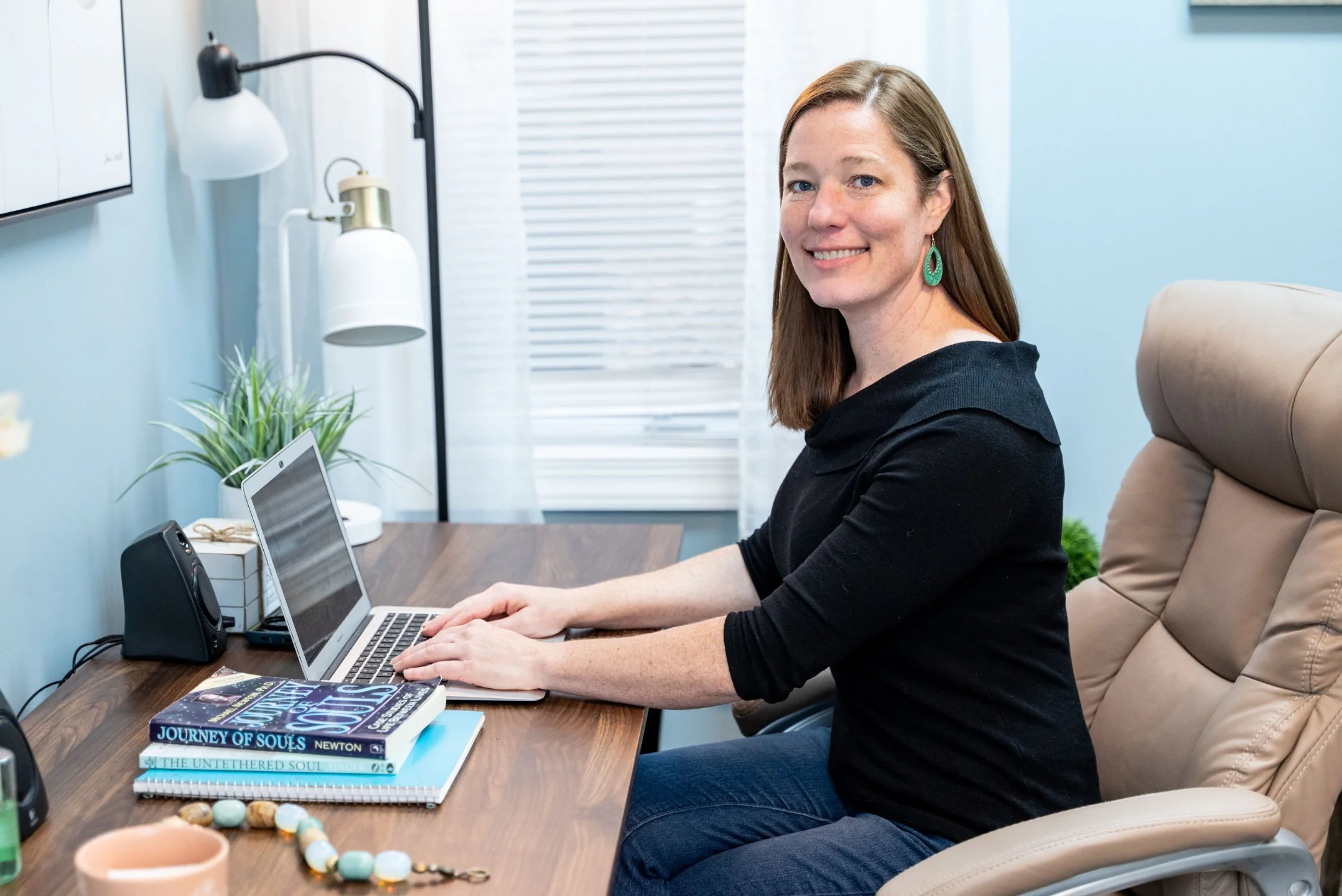 Hypnotherapist and hypnotherapy certification instructor Jen Catlin sitting in her office in Cary, NC at her desk preparing for hypnotherapy training and a group past life regression
