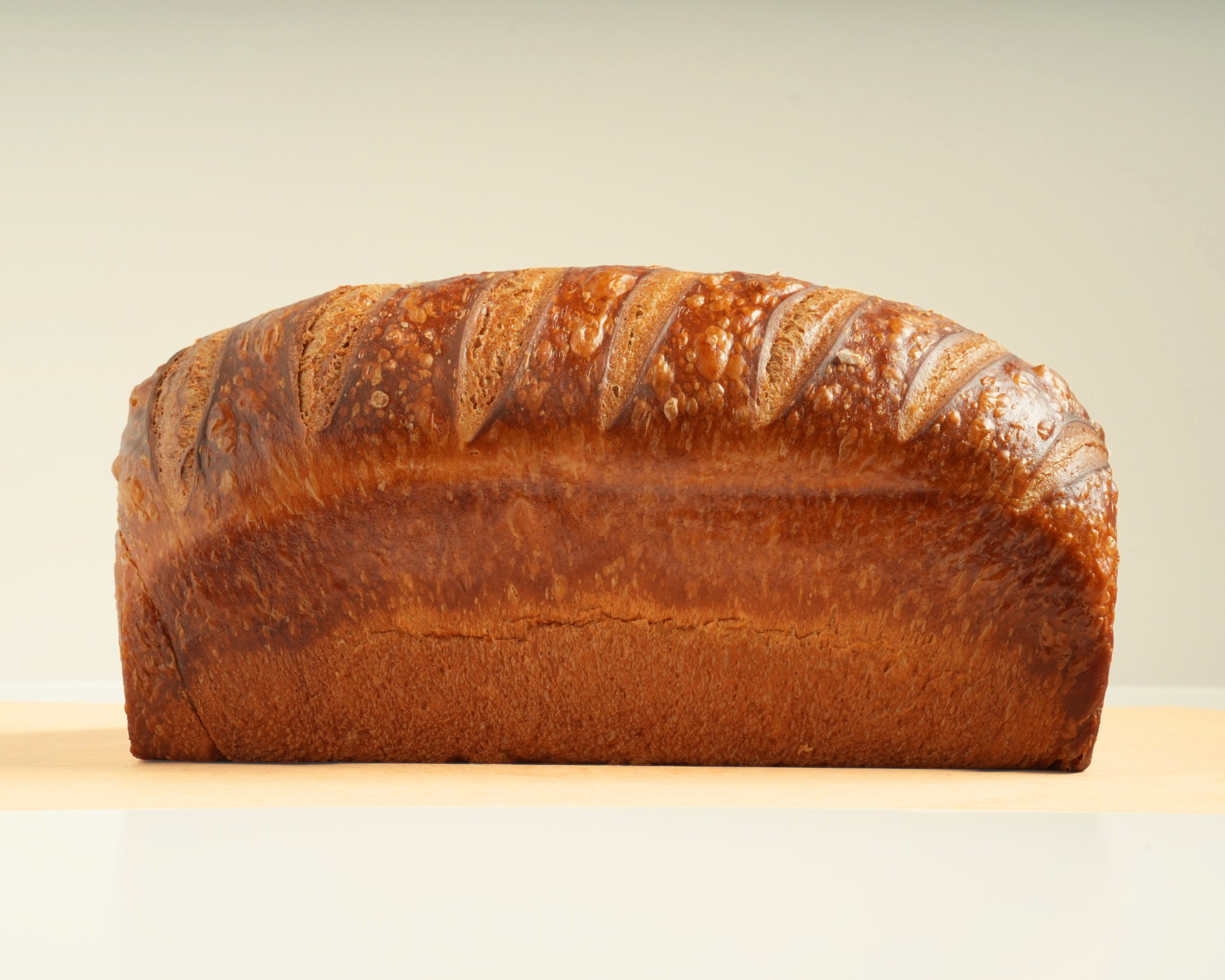 Loaf of bread with a golden brown crust on a light-colored surface.