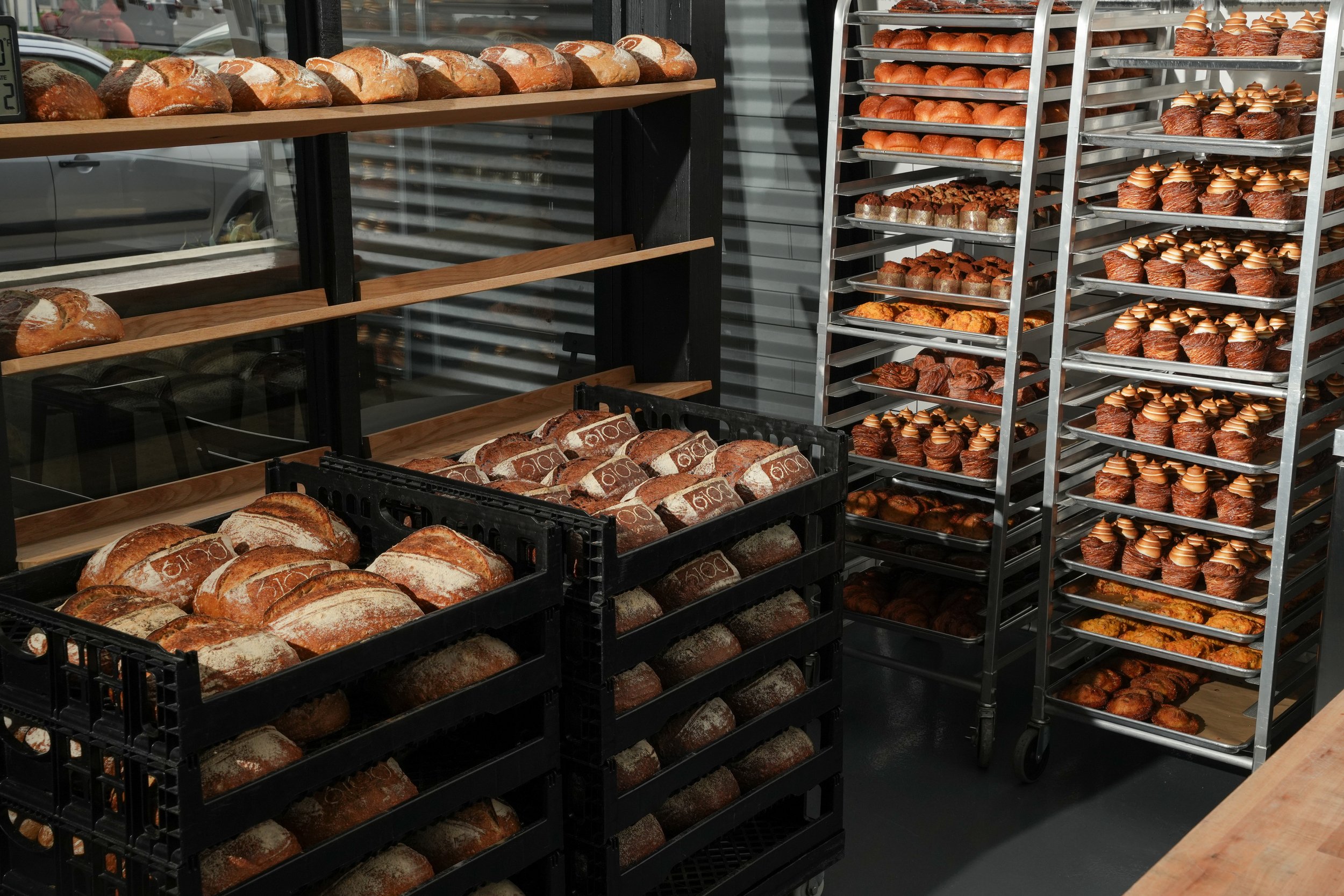 Bakery display with shelves of bread and racks of various pastries and muffins.